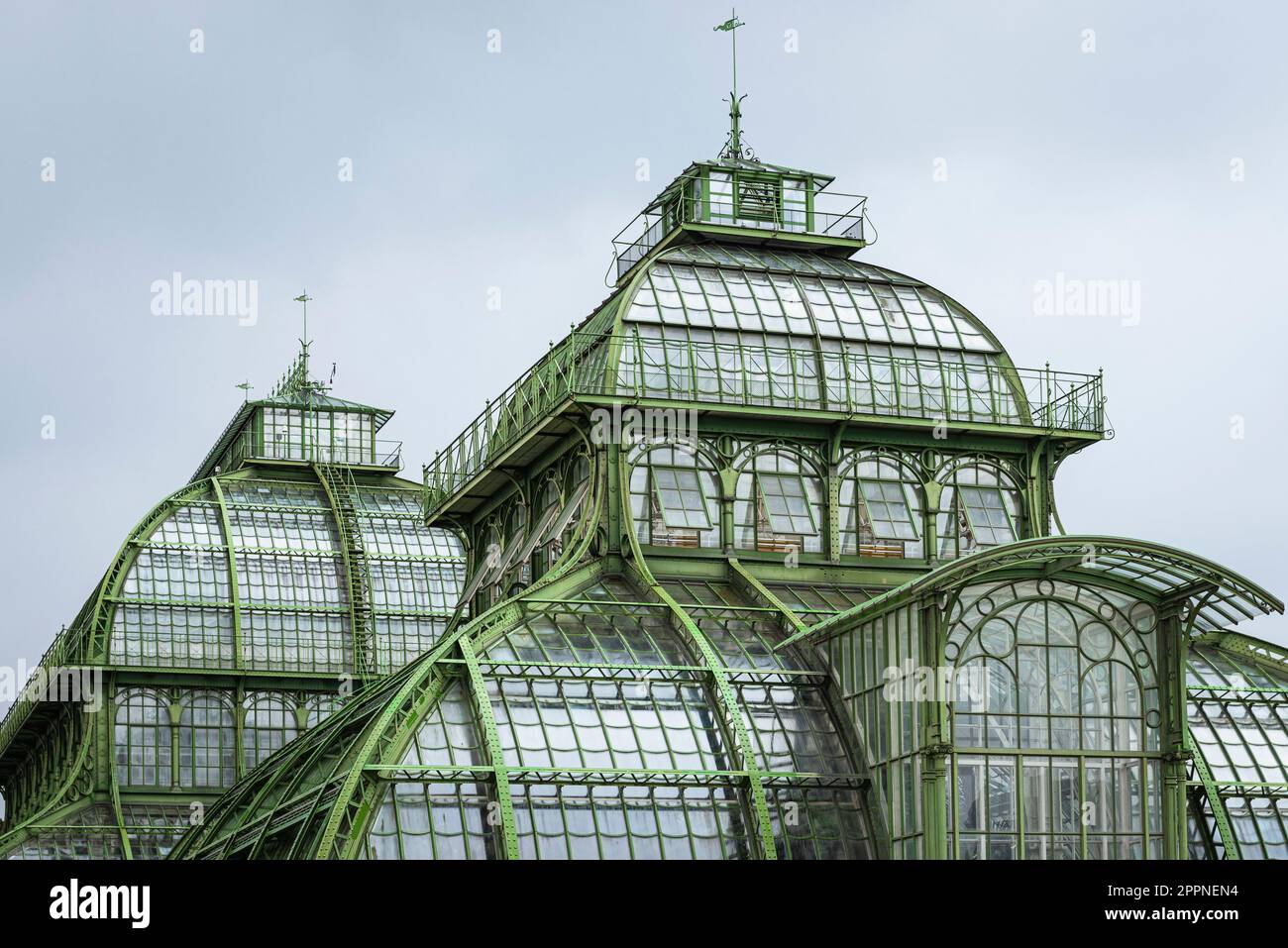 Die Kuppeln des Palmenhauses aus Schmiedeeisen, Gusseisen und Glas im Schlosspark Schönbrunn unter grauem Himmel, Wien, Österreich Stockfoto