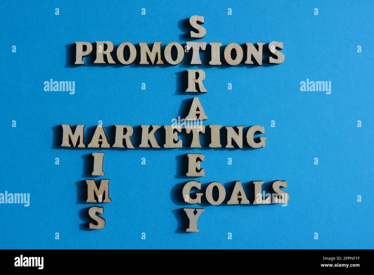 Marketing, Promotions, Strategie, Ziele, Ziele, Wörter in hölzernen Buchstaben sind Kreuzworträtsel, isoliert auf blauem Hintergrund Stockfoto
