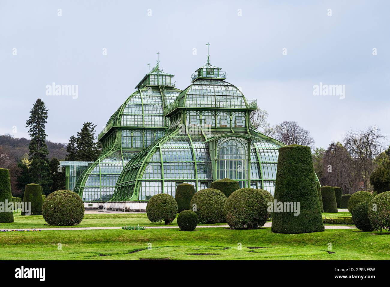 Die Kuppeln des Palmenhauses aus Schmiedeeisen, Gusseisen und Glas im Schlosspark Schönbrunn unter grauem Himmel, Wien, Österreich Stockfoto