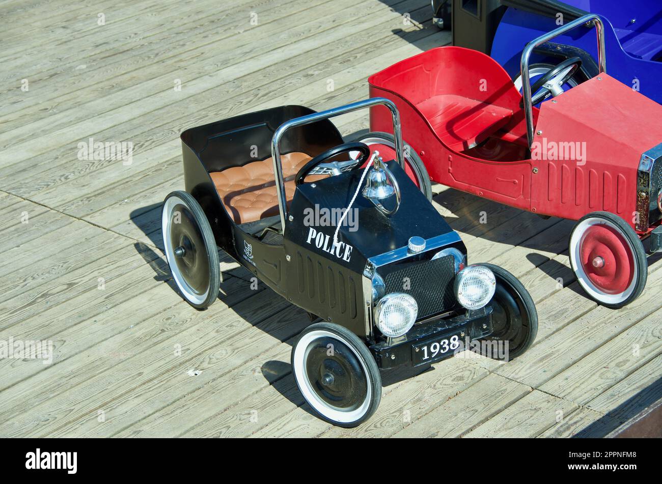 Treten Sie Autos in altem Stil für Kinder zum Spielen im Freien auf dem Spielplatz aus Holz in die Pedale. Stockfoto