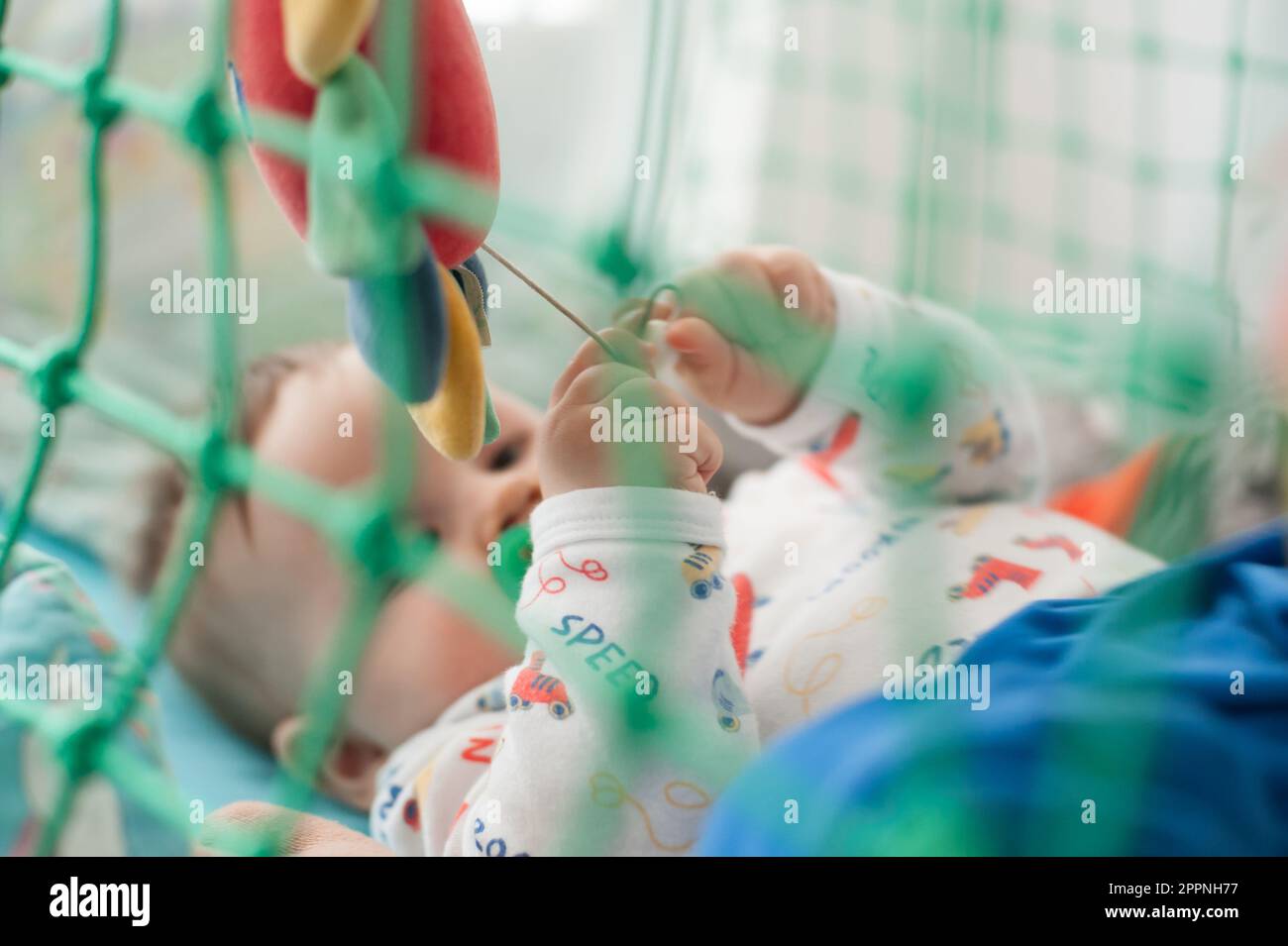 Ein süßer kleiner Junge schläft friedlich und entspannt auf seinem Bett mit Spielzeug. Draufsicht des Kinderbetts. Liebe und Familiengefühle Stockfoto