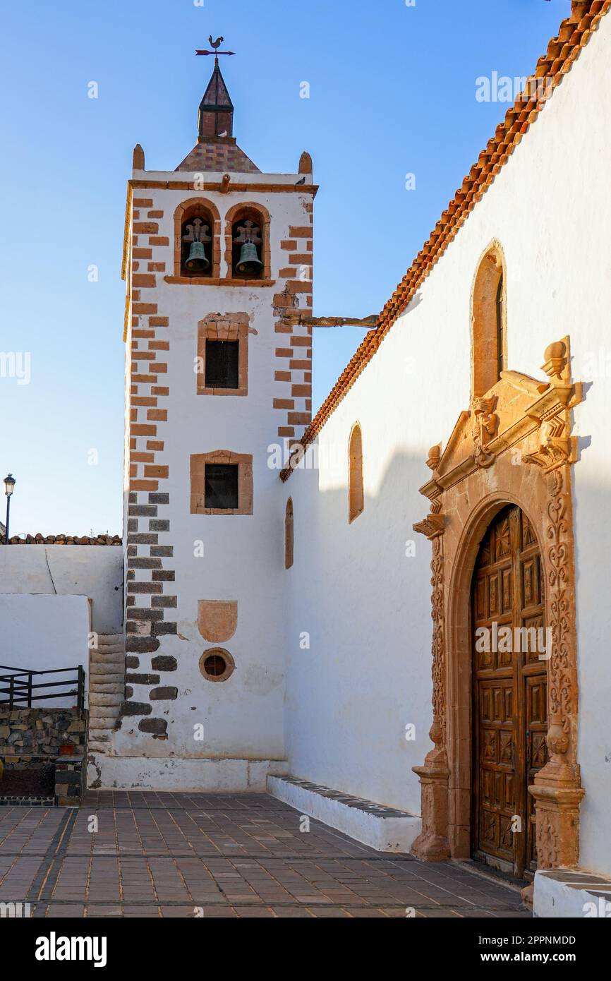 Glockenturm der Kirche der Heiligen Maria von Betancuria, umgeben von Palmen in der ehemaligen Hauptstadt der Insel Fuerteventura auf den Kanaren, Spai Stockfoto