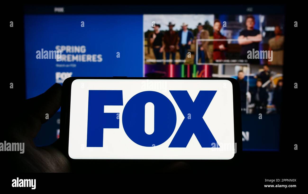 Person, die ein Smartphone mit dem Logo des US-amerikanischen Massenmedienunternehmens Fox Corporation auf dem Bildschirm vor der Website hält. Konzentrieren Sie sich auf das Display des Telefons. Stockfoto