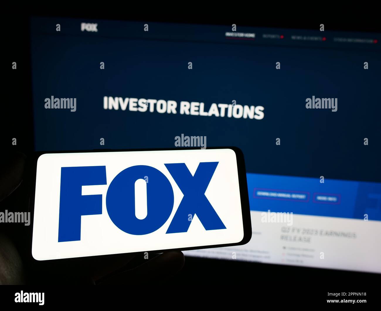 Person, die ein Mobiltelefon mit dem Logo des US-amerikanischen Massenmedienunternehmens Fox Corporation auf dem Bildschirm vor der Unternehmenswebseite hält. Konzentrieren Sie sich auf das Display des Telefons. Stockfoto