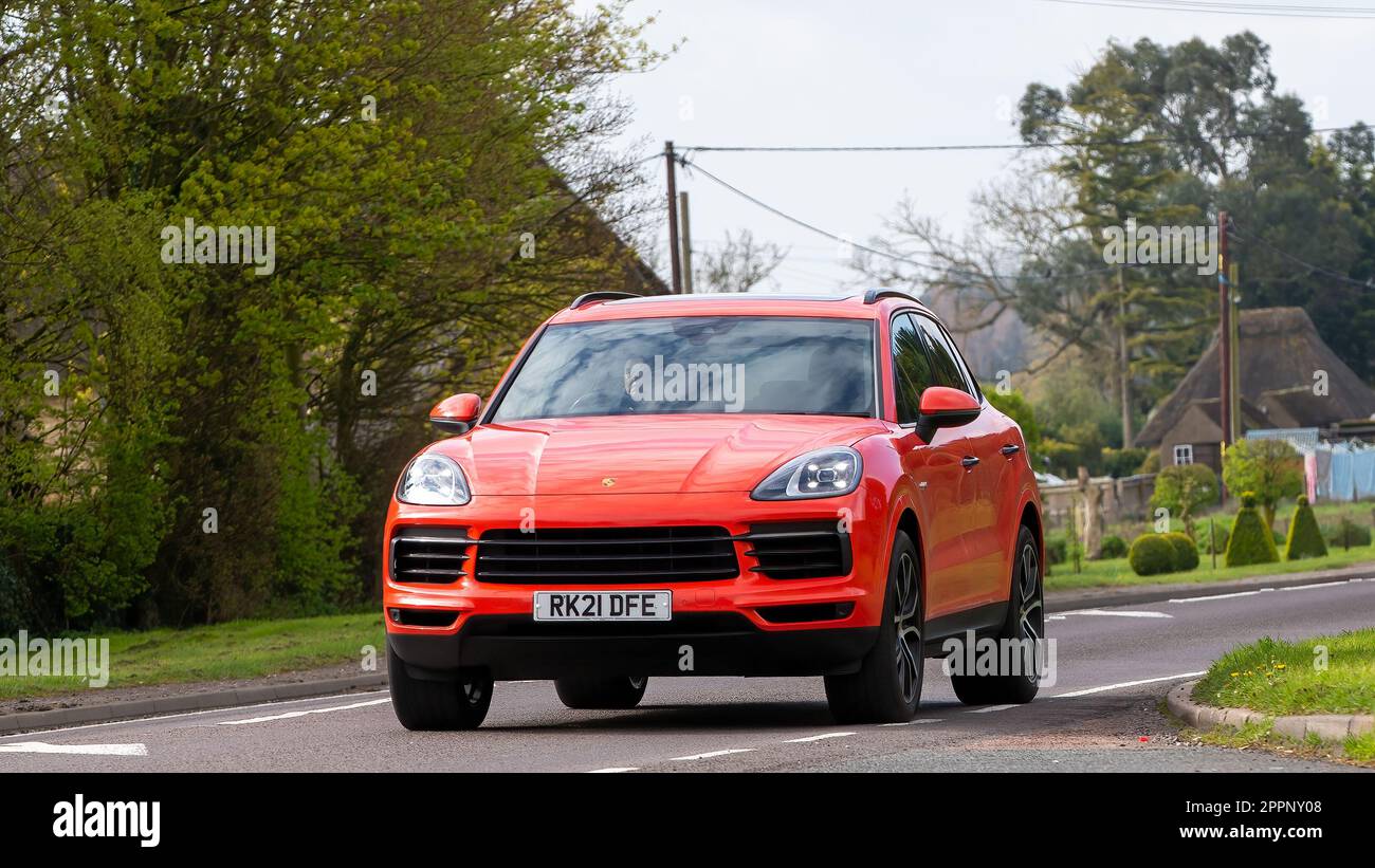 Bicester, Oxon, Großbritannien - April 23. 2023. 2021 m orangefarbener PORSCHE CAYENNE Hybrid-Elektrowagen, der durch ein englisches Dorf fährt Stockfoto