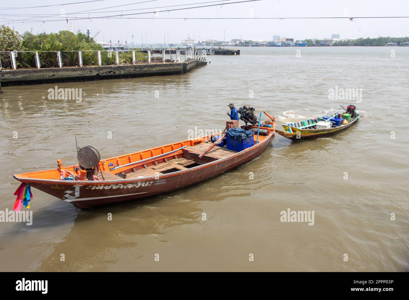 SAMUT PRAKAN, THAILAND, MÄRZ 14 2023, Ein Motorboot aus Holz zieht ein kleineres Boot auf dem Fluss Chao Phraya Stockfoto