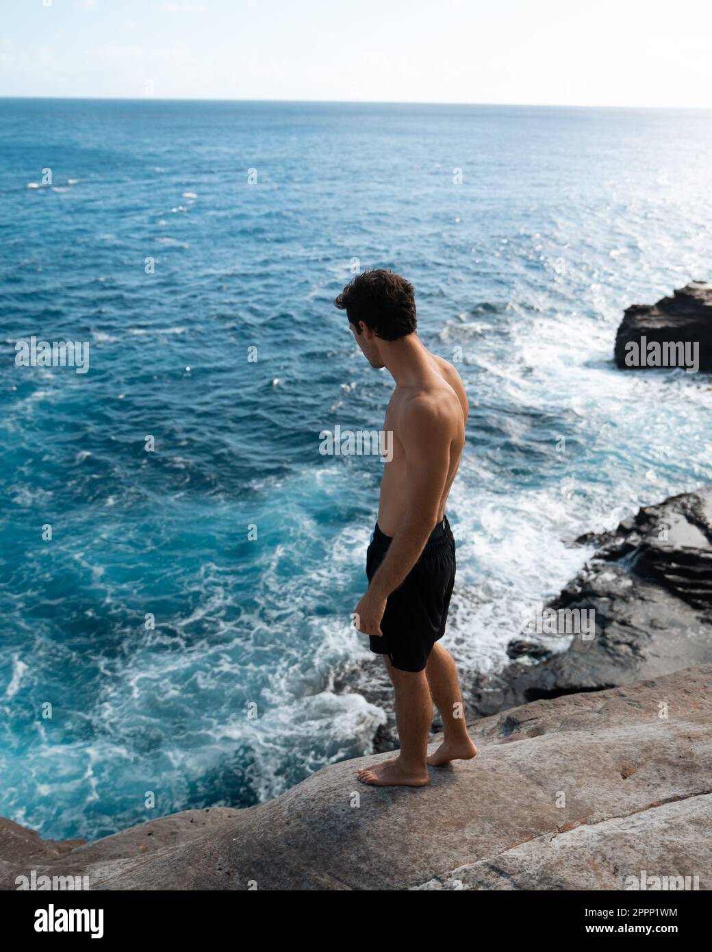 Ein Mann, der von der Spitting Cave auf Oahu, Hawaii, springt. Hochwertiges Foto Stockfoto