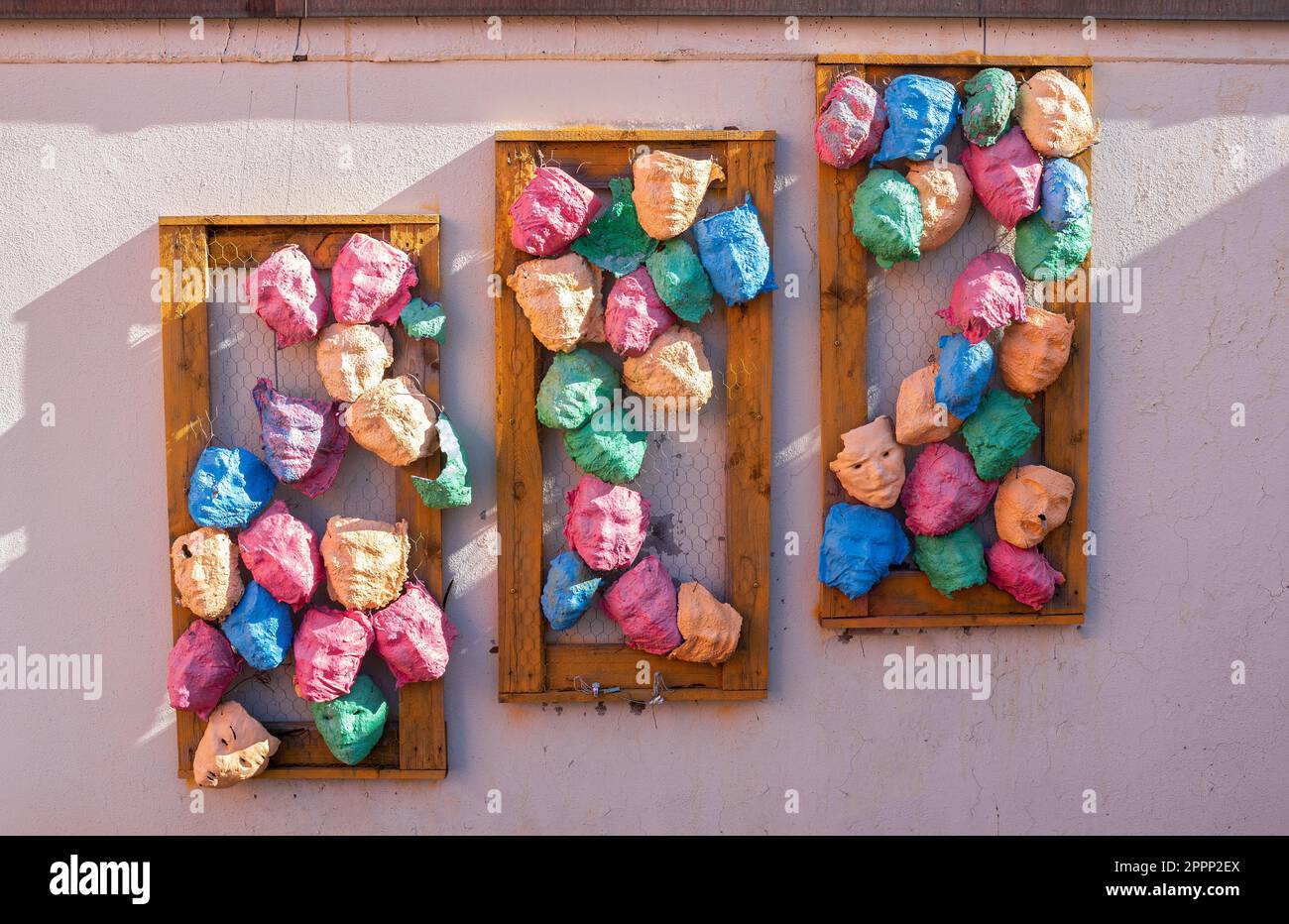 Dekorative bunte Karnevalsmasken an der rosafarbenen Wand eines Hauses in Donaueschingen Stockfoto