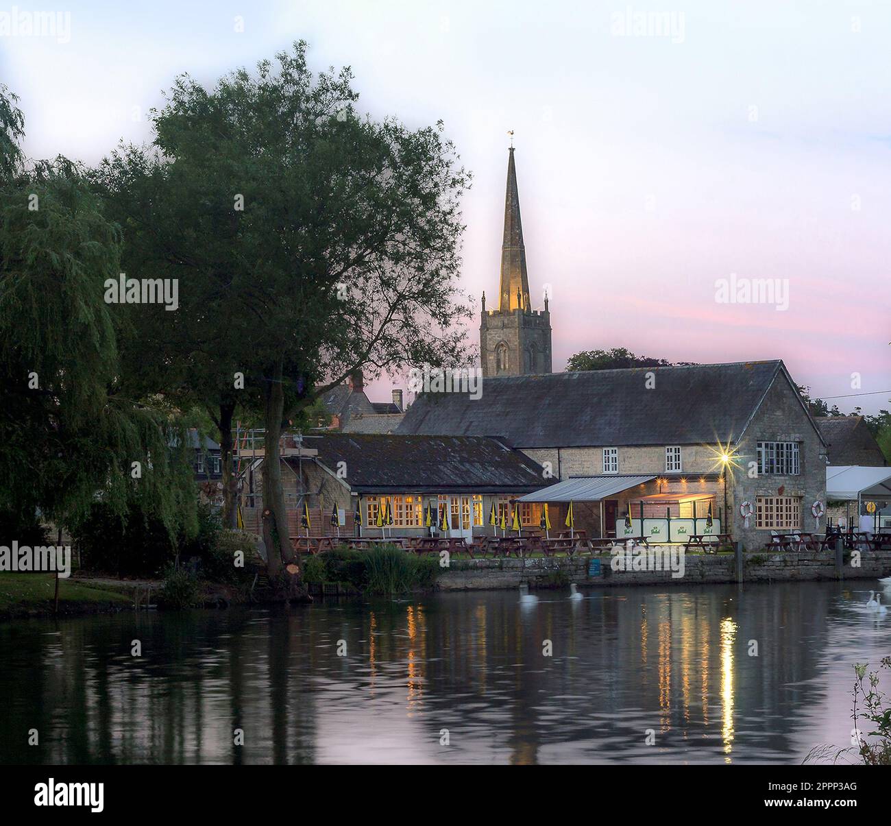 LECHLADE-ON-THAMES, GLOUCESTERSHIRE, Großbritannien - 02. JULI 2008: Blick über die Themse bei Abendlicht in Richtung Riverside Pub und St Lawrence Church Stockfoto