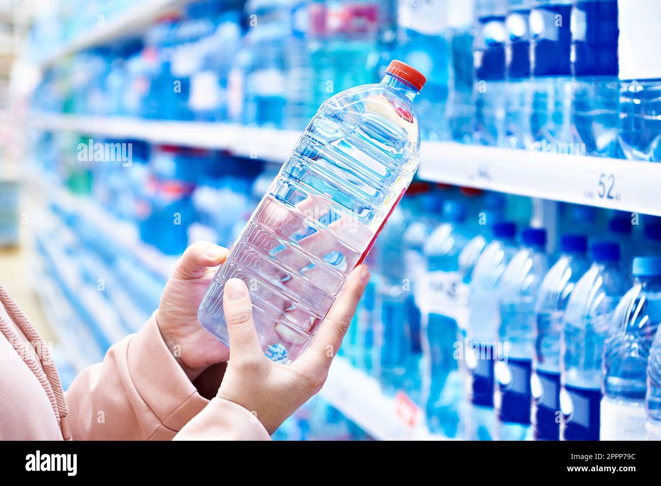Plastikflaschen-Trinkwasser in den Händen des Käufers im Geschäft Stockfoto