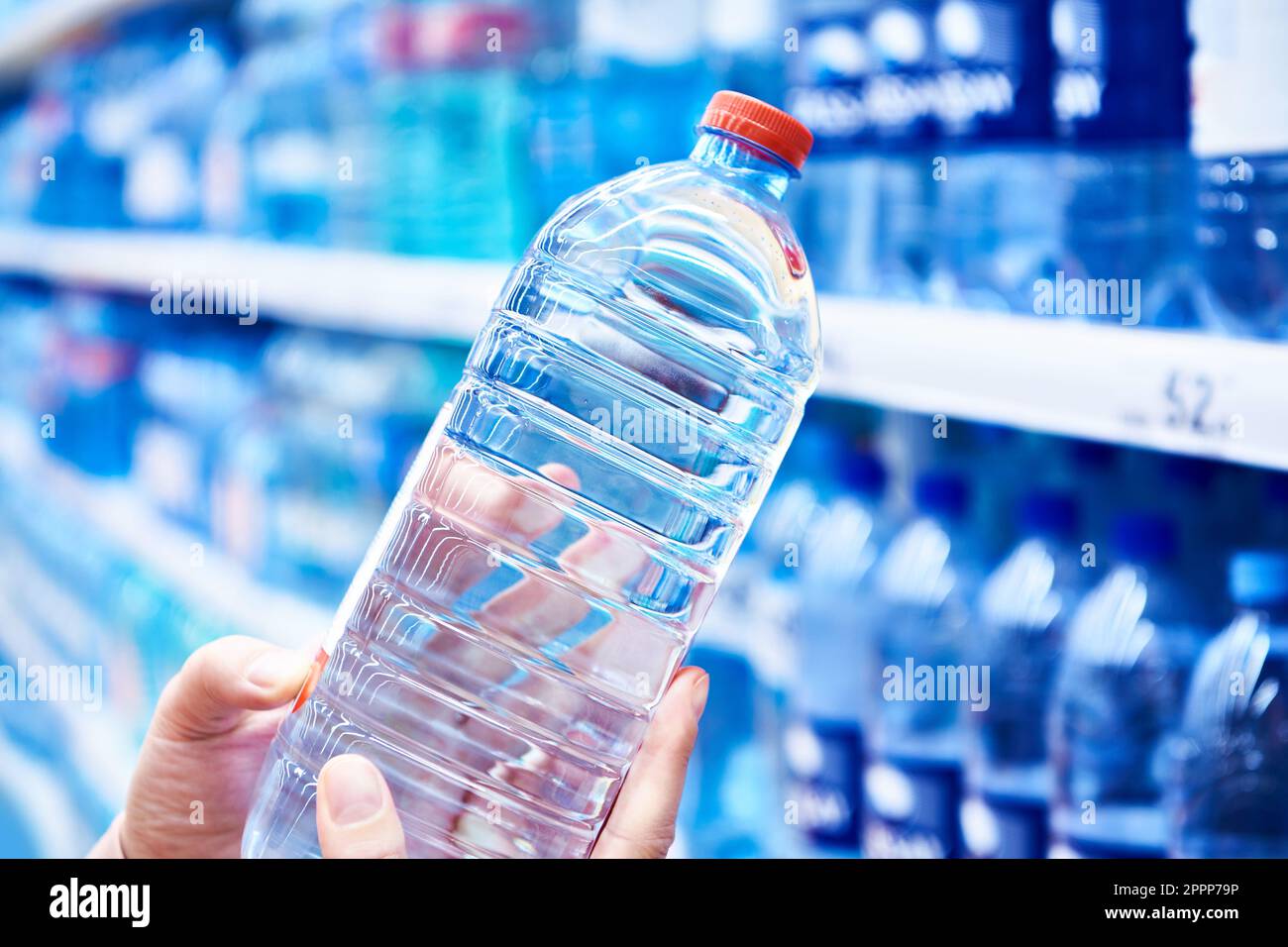 Plastikflaschen-Trinkwasser in den Händen des Käufers im Geschäft Stockfoto