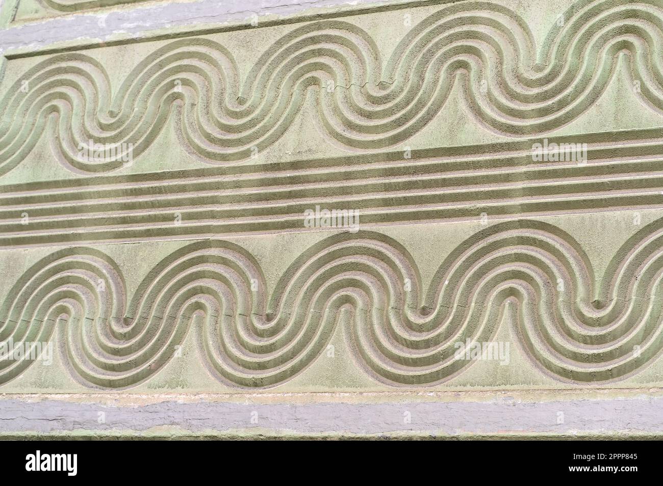 Die Textur einer weißen Betonwand mit einem Muster wellenförmiger Linien. Wandhintergrund Stockfoto