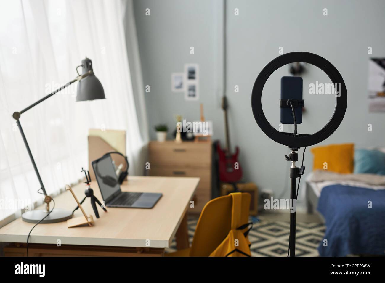 Runder Rahmen mit Smartphone-Halterung, der am Arbeitsplatz eines Designers, Freiberuflers oder Studenten steht, mit Lampe über Laptop im Schlafzimmer Stockfoto
