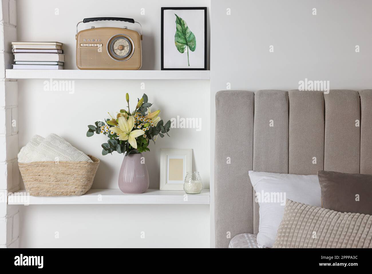 Stilvolle Vase mit Blumen, Retro-Radio und Innenregale. Innenelemente des Schlafzimmers Stockfoto