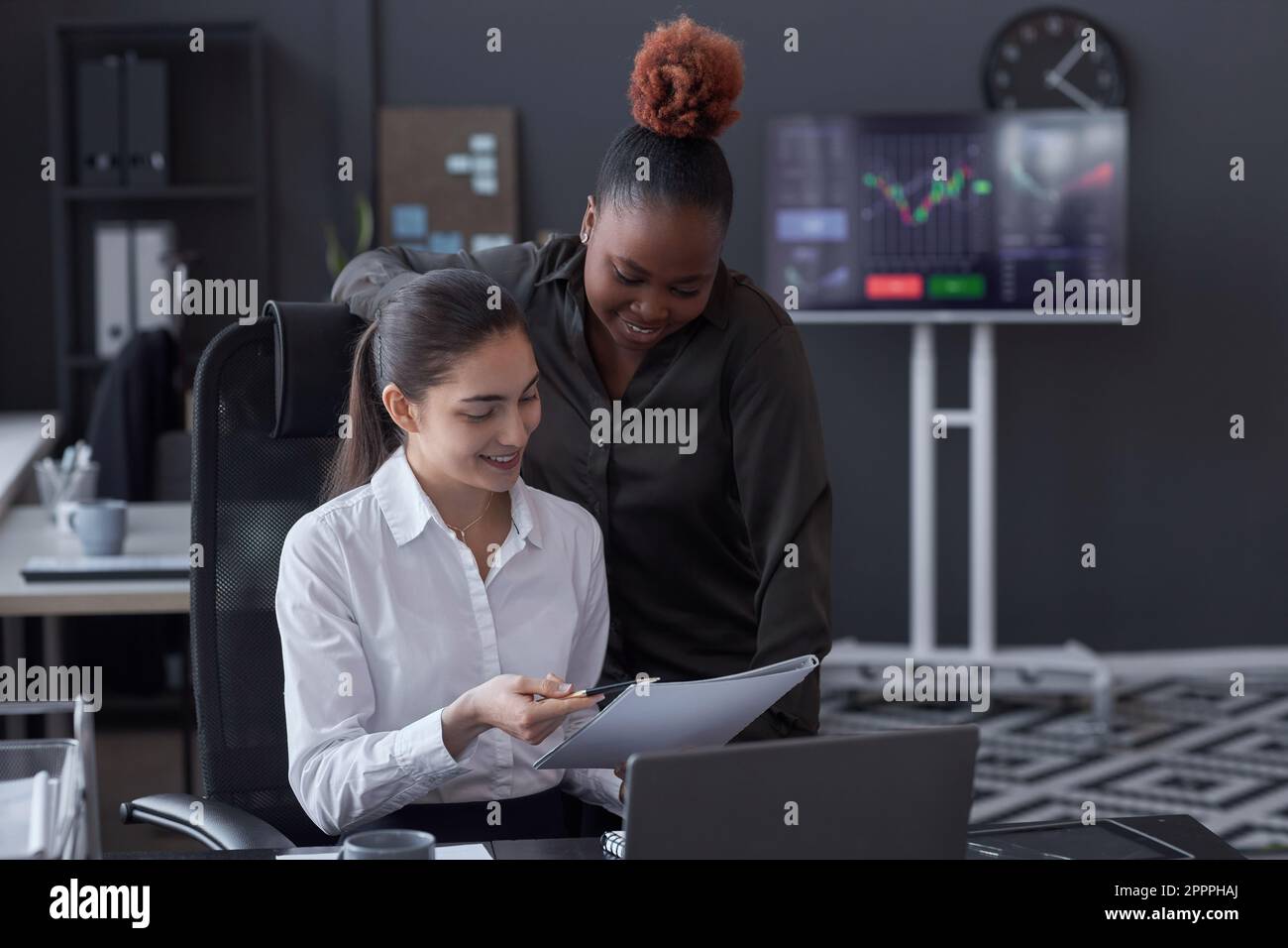 Junge Kollegen analysieren Finanzdokumente zusammen, während sie am Tisch im Maklerbüro sitzen Stockfoto