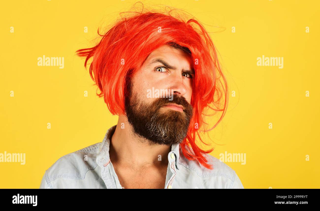 Ein bärtiger Mann mit roter Perücke. Ein gutaussehender Mann mit Bart und Schnurrbart in bunter Perücke. Zeit für die Party. Modekonzept. Werbung im Friseursalon. Hipster ist da Stockfoto