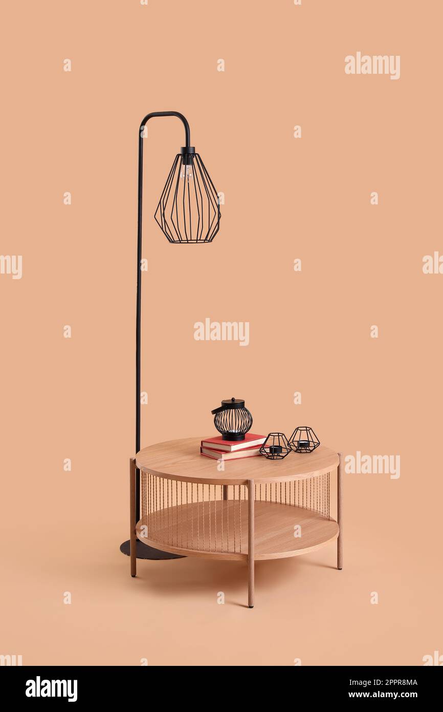 Kaffeetisch aus Holz mit Kerzenhalter und Lampe auf beigefarbenem Hintergrund Stockfoto