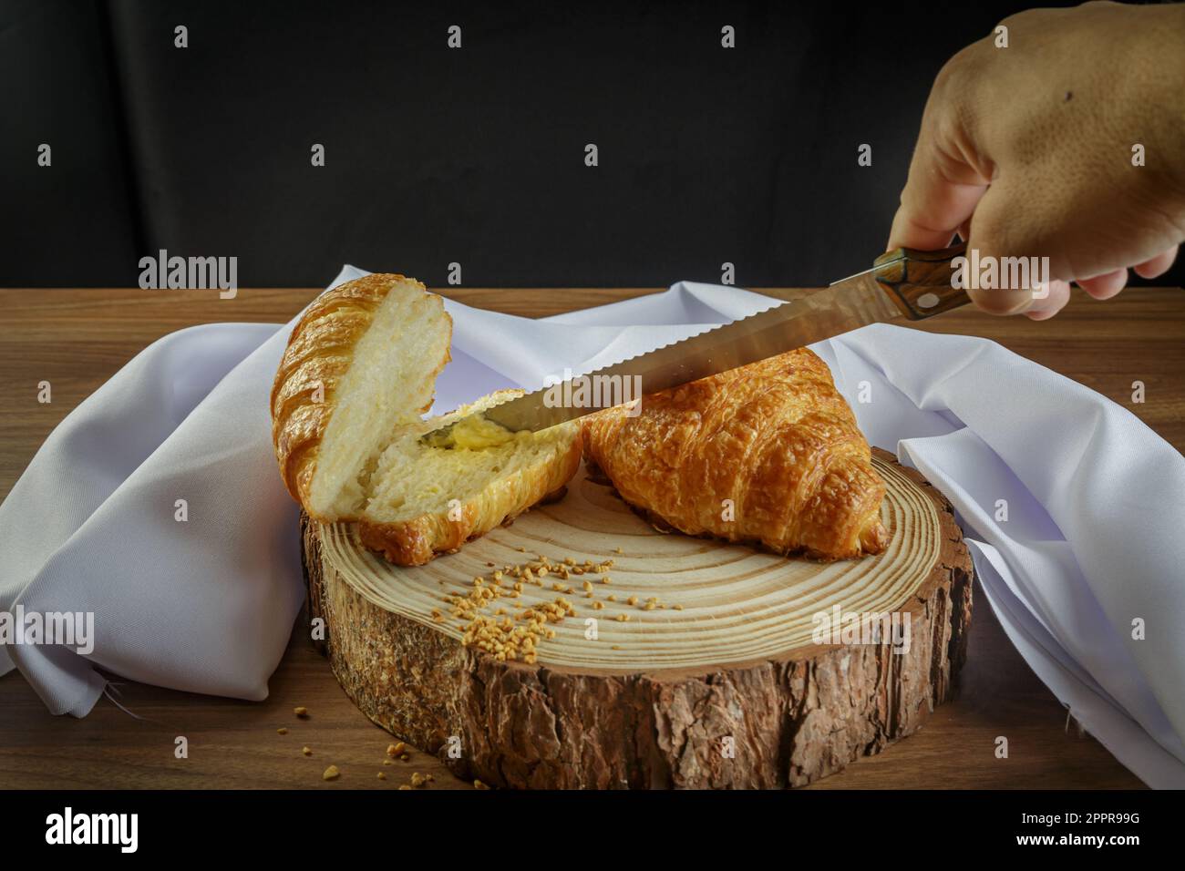 Köstliche Croissants auf einem Holzkoffer, mit weißem Handtuch und Butter auf den geschnittenen Croissants - perspektivischer Blick. Stockfoto