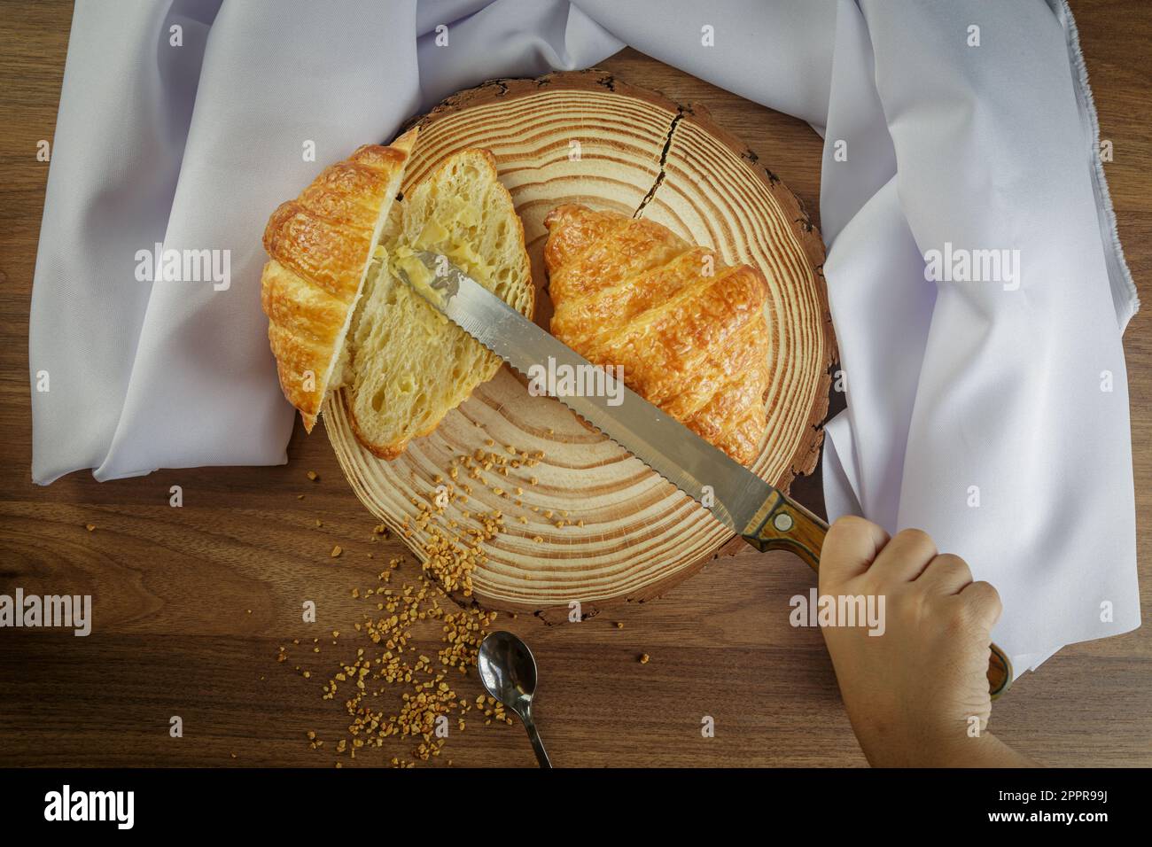 Köstliche Croissants auf einem Holzkoffer, mit weißem Handtuch und Butter auf den geschnittenen Croissants - Draufsicht. Stockfoto
