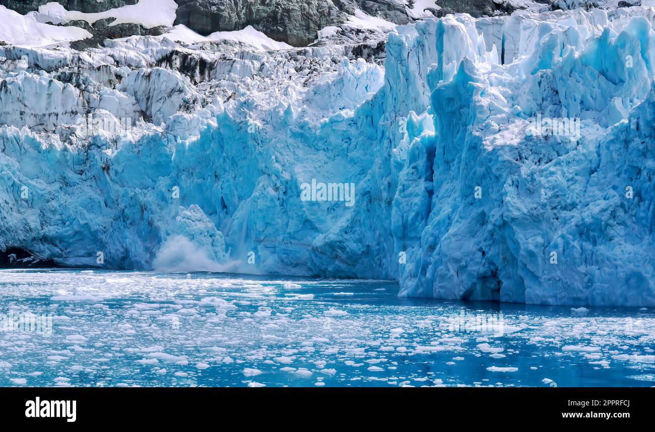 Nahaufnahme eines Gletschergesichts, während ein Eisstück nach dem Abkalben ins Wasser spritzt. In Drygalski Fjord auf South Georgia Island. Stockfoto