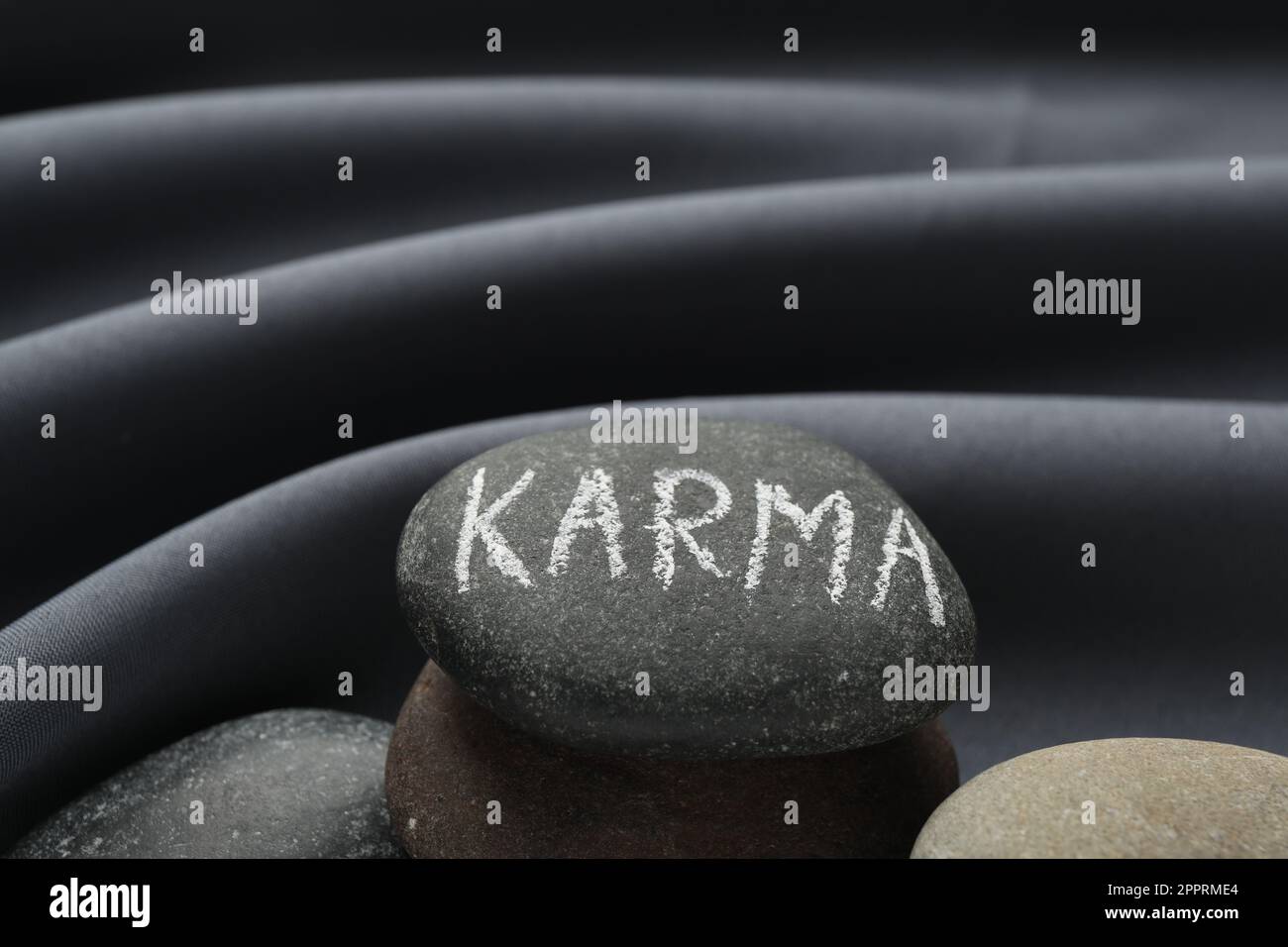 Steine mit dem Wort Karma auf grauem Stoff, Nahaufnahme Stockfoto