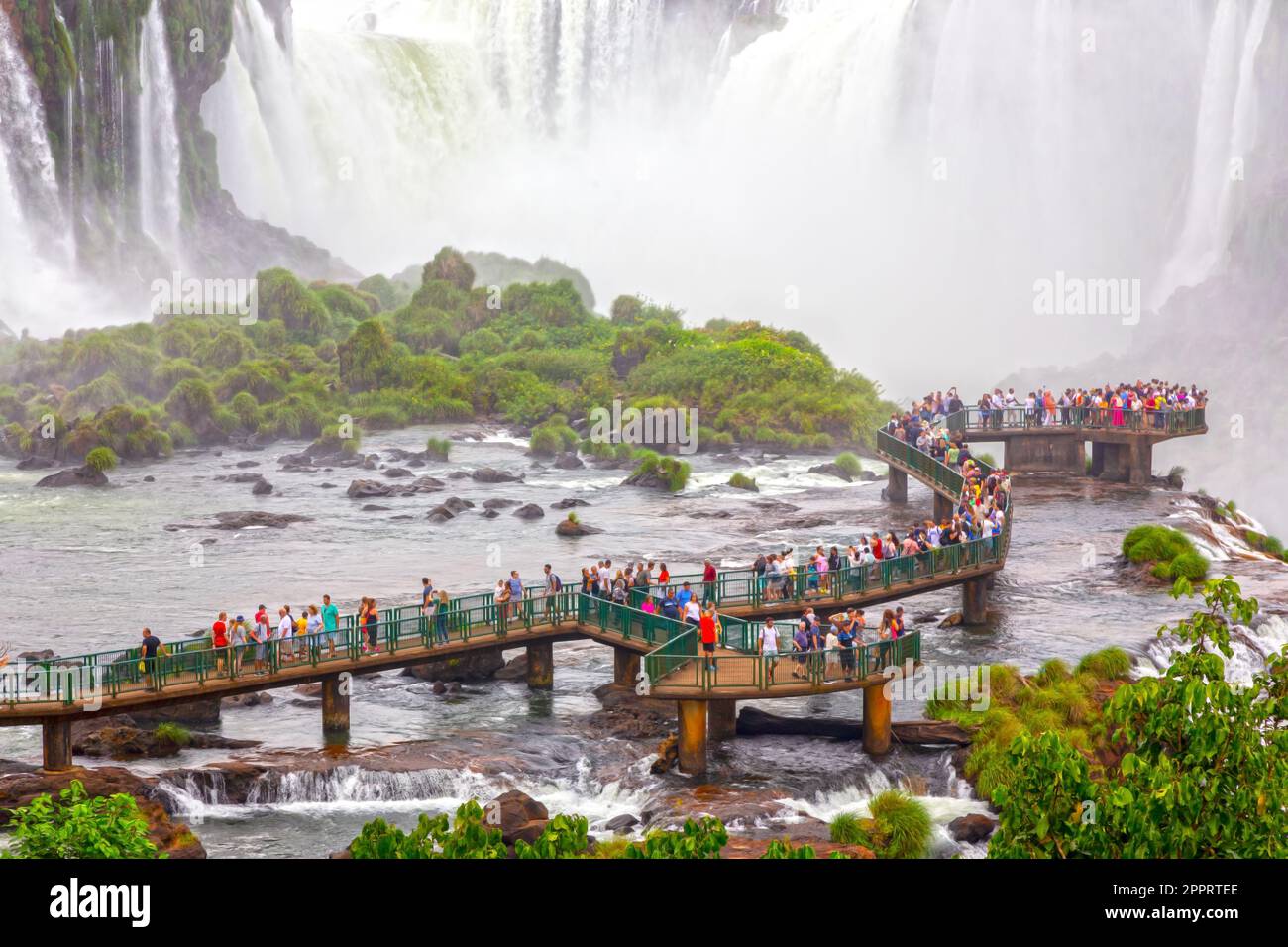 Touristen auf einem Hängebahn bewundern den Blick auf Garganta Del Diablo oder Devil's Throat, die berühmte riesige U-förmige Kaskade in den weltberühmten Iguazu Falls Stockfoto