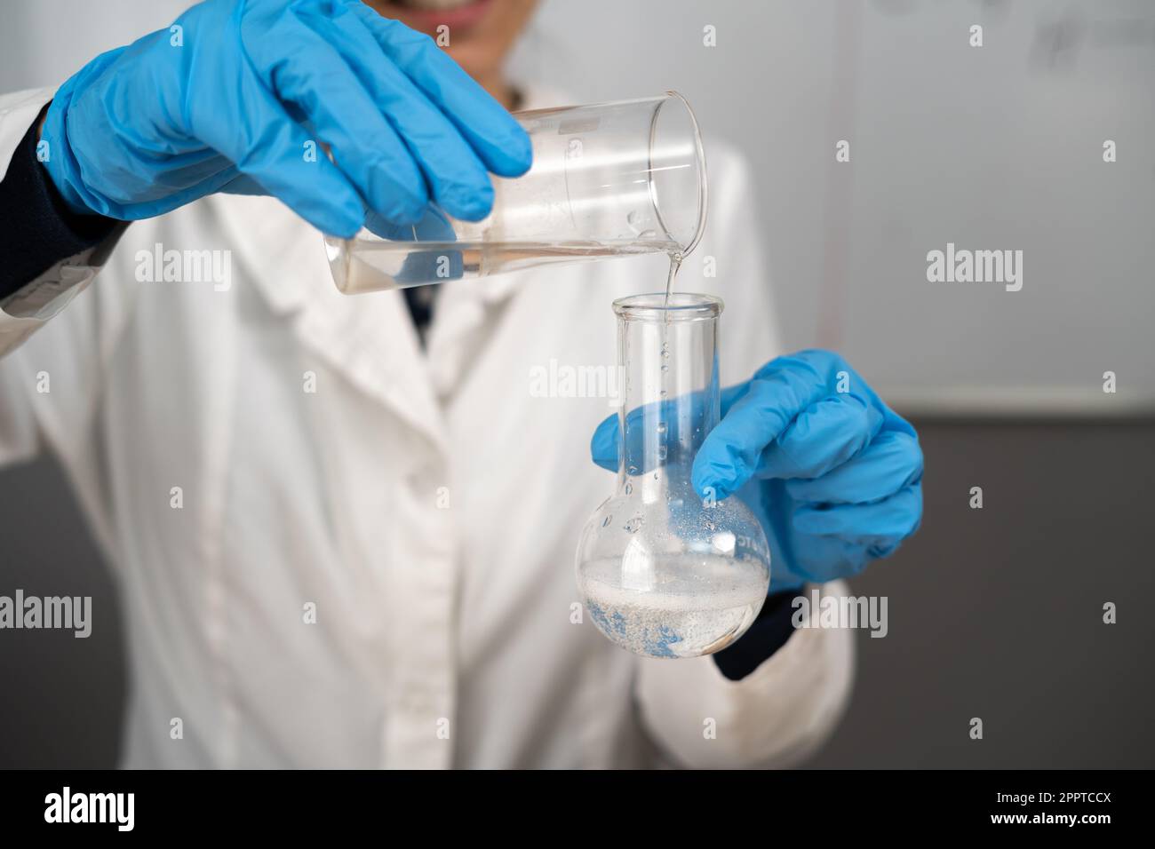 Experimente in einem Chemielabor, Nahaufnahme. Hände und Glaskolben. Durchführung eines Experiments im Labor. Stockfoto