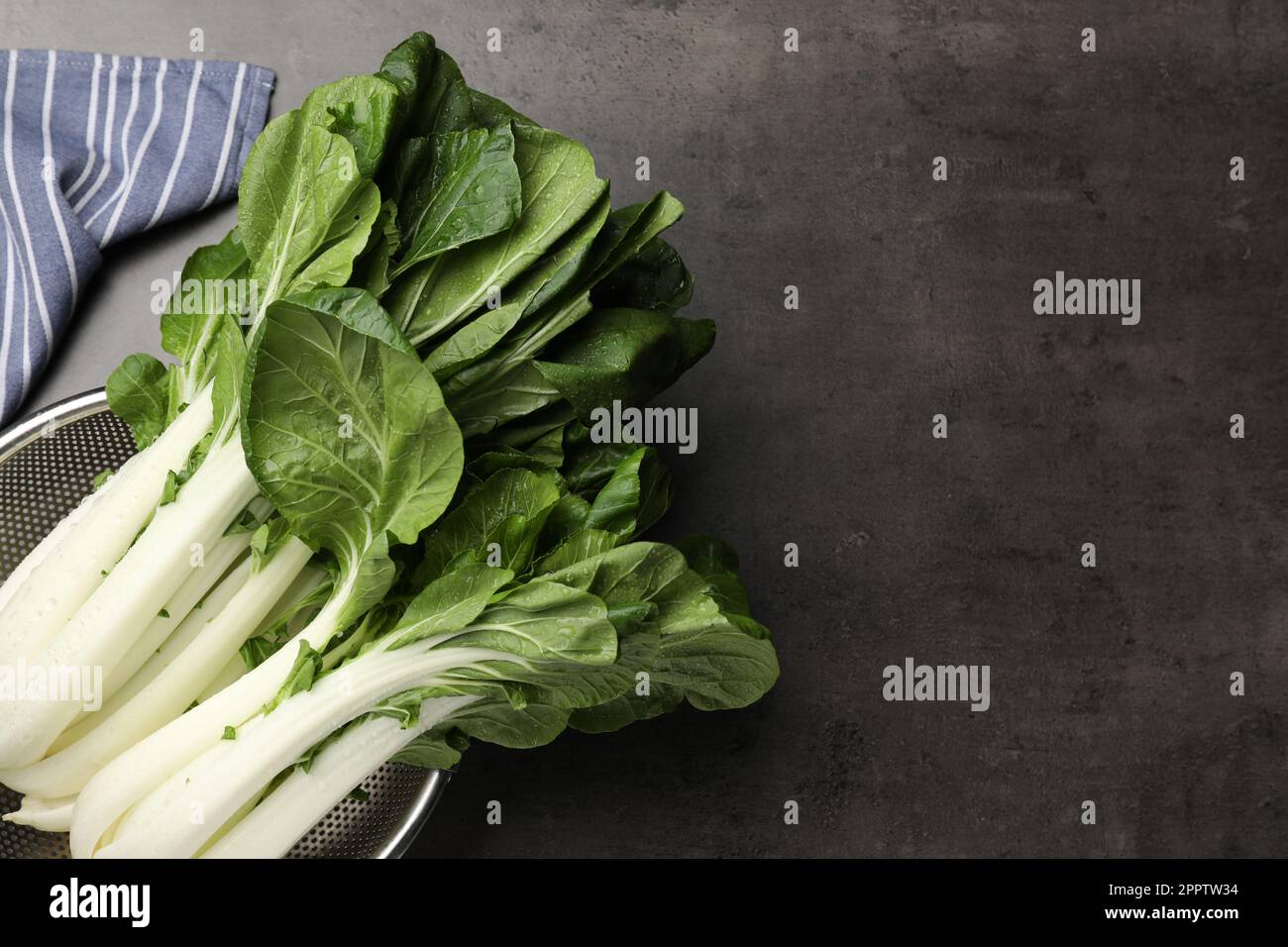 Frischer grüner pak Choy Kohl mit Wassertropfen im Sieb auf grauem Tisch, Draufsicht. Platz für Text Stockfoto