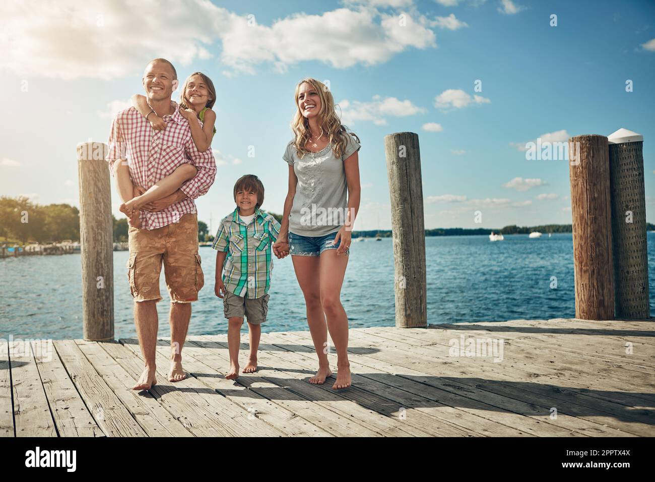 Zeit mit der Familie zu verbringen, ist Zeit, die gut verbracht wird. Eine junge Familie auf einem Pier am See. Stockfoto