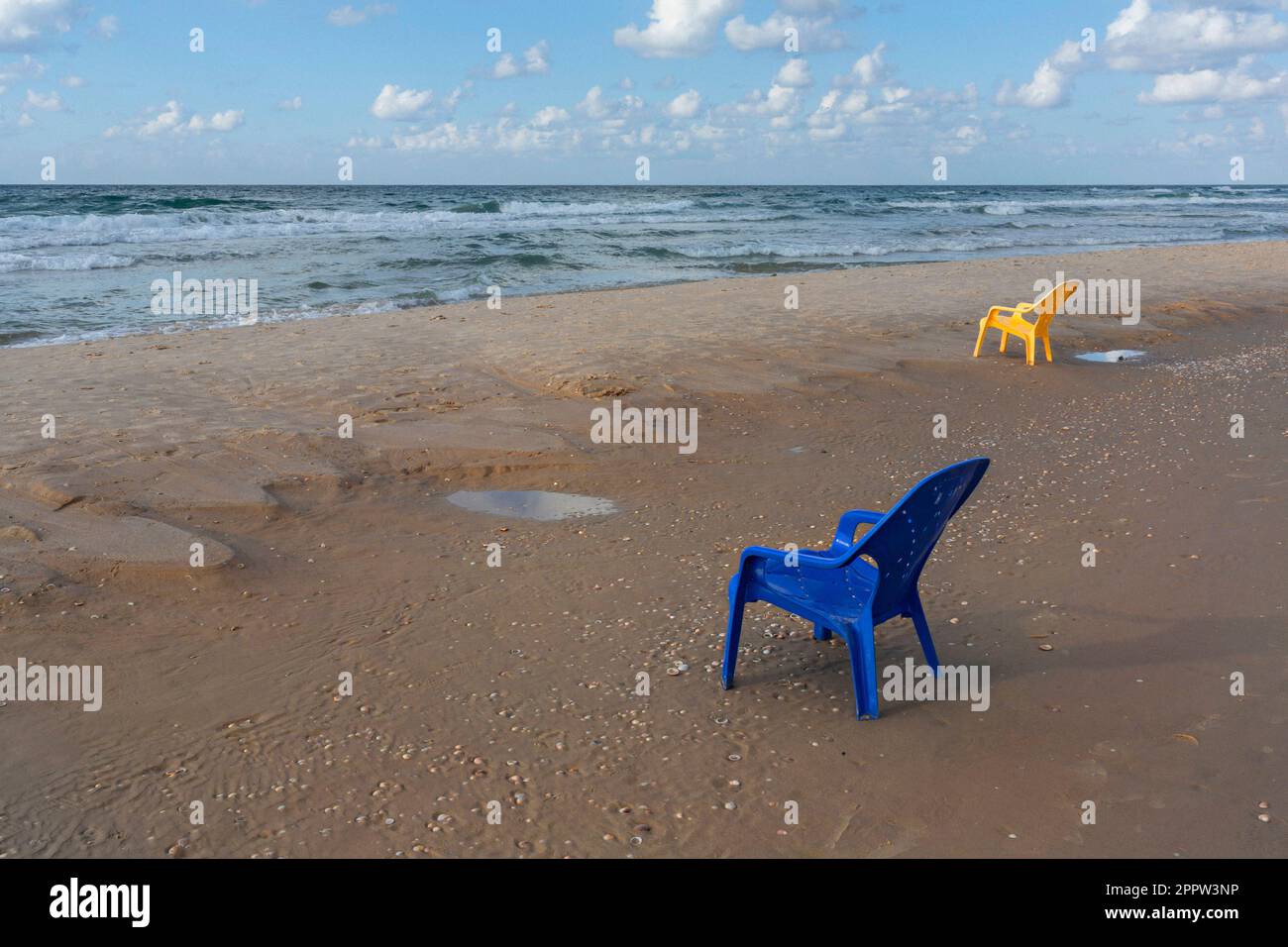 Plastikstühle am nassen Sandstrand des Ozeans, bat Yam, Israel Stockfoto