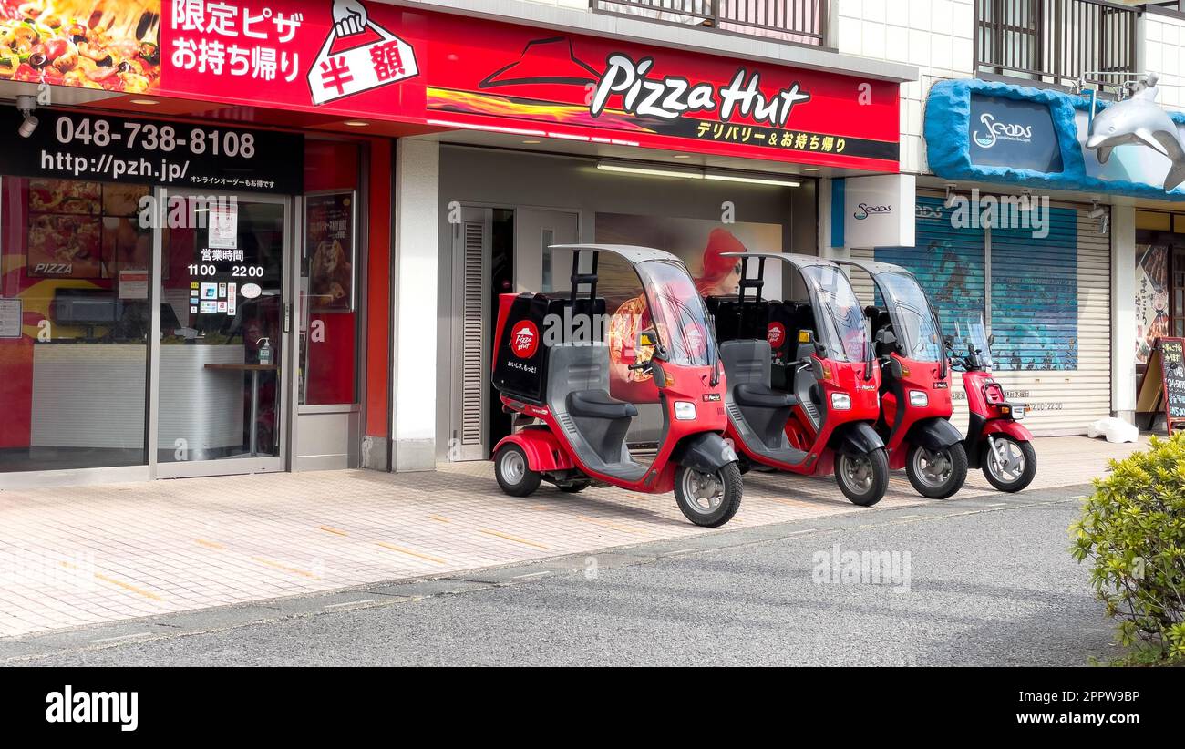 Ein Seitenbild von vier 3-rädrigen Pizza Hut Liefermotorrädern mit Dächern und einer Aufbewahrungsbox hinten mit Bildern des roten Pizza Hut Logos Stockfoto