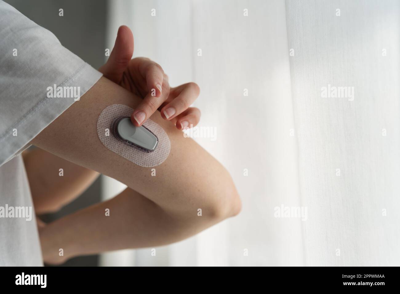 Nahaufnahme einer Frau, die ein kontinuierliches Blutzuckermessgerät an ihren Arm anlegt Stockfoto