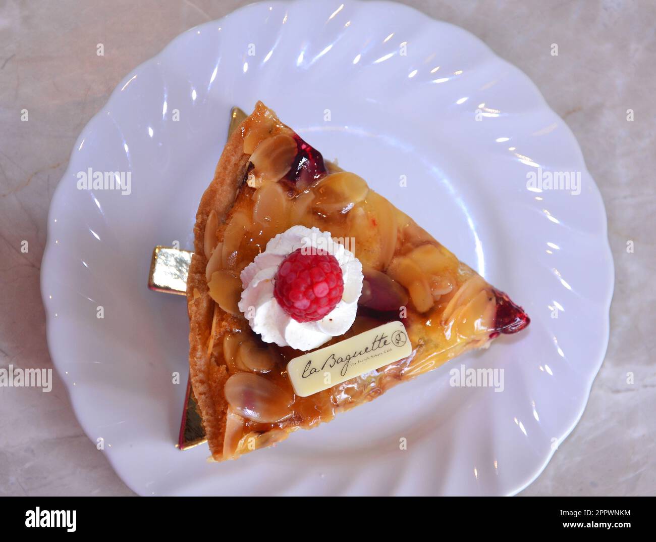 Blick von oben auf eine köstliche Himbeer-Mandel-Torte auf einem weißen Teller im La Baguette Bakery Cafe in Pattaya, Thailand. Stockfoto