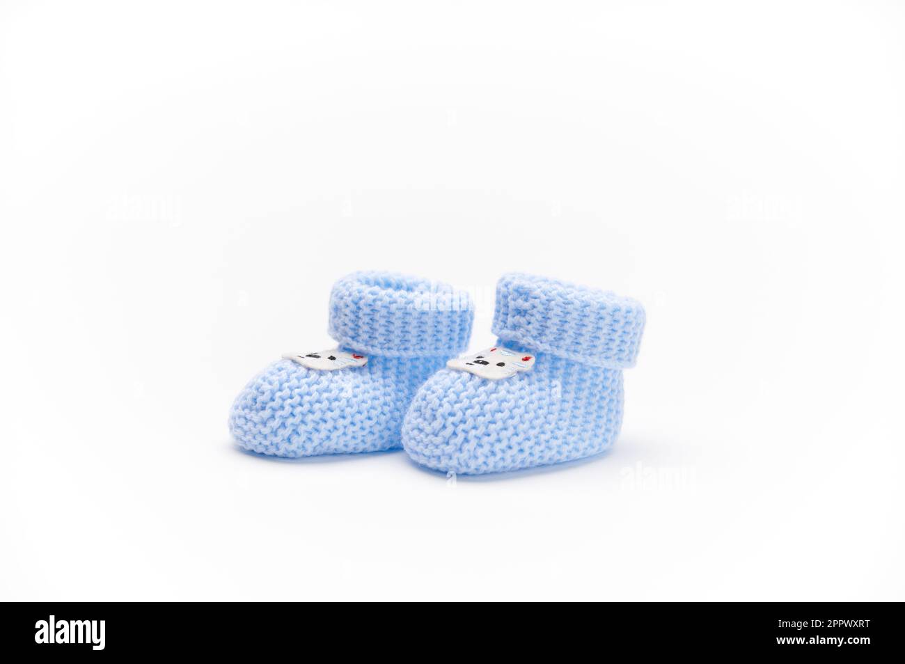 Ein Paar handgefertigte blaue gestrickte Babyschühchen, isoliert auf weißem Hintergrund. Neugeborenenbekleidung und Schwangerschaftskonzept. Kopierbereich für Werbetext. F Stockfoto