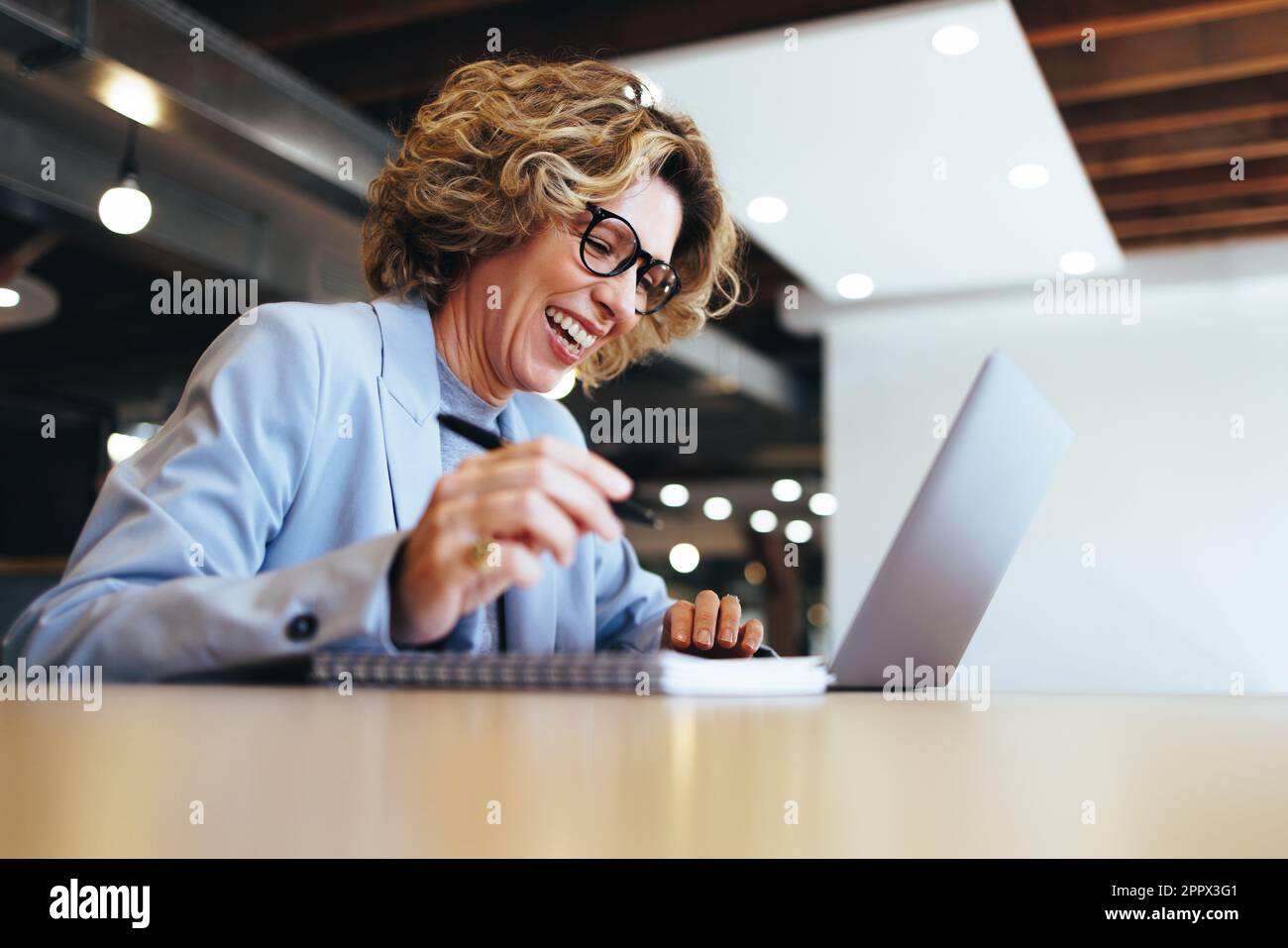 Glückliche Geschäftsfrau, die ein virtuelles Meeting mit ihrem Team in einem Büro abhält. Professionelle Geschäftsfrau, die ein Videogespräch mit einem Laptop führt. Reife weibliche PR Stockfoto