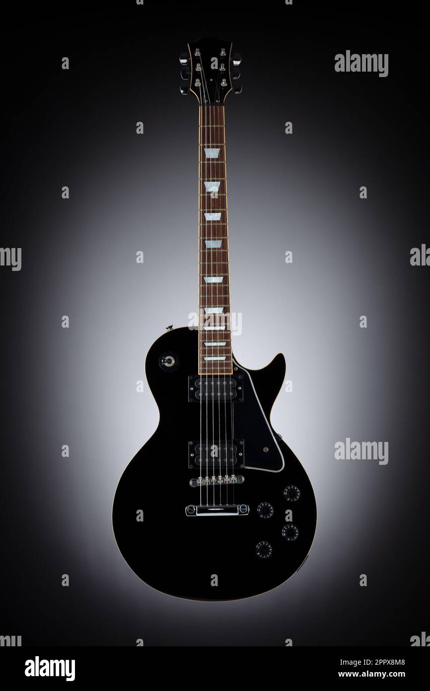 Schwarze Gitarre isoliert und schwimmend auf grauem Hintergrund Stockfoto