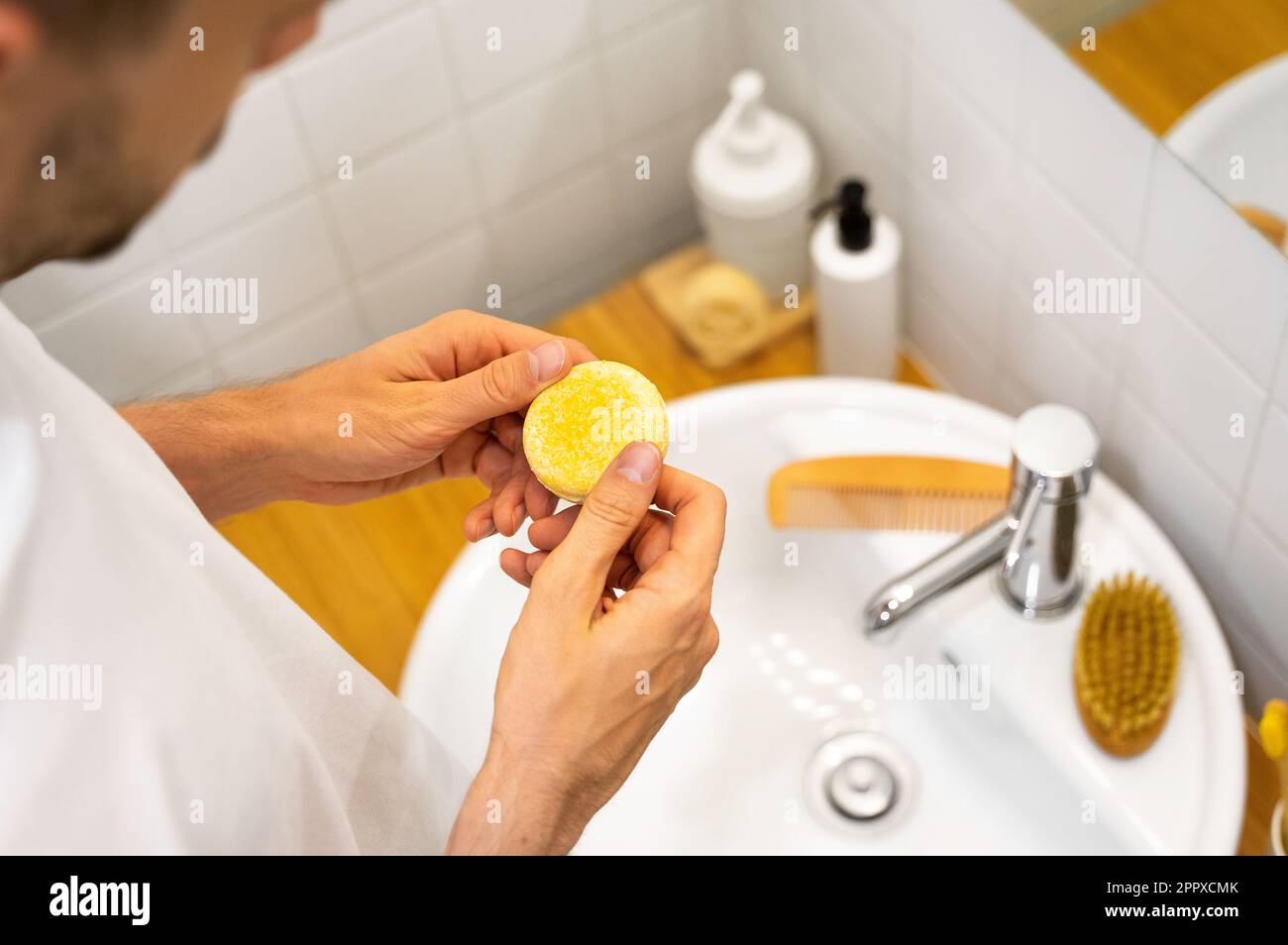 Ein solider Shampoo-Riegel in Männerhänden. Plastikfrei, kein Abfall, geringe Wassermenge. Nachhaltige Haarpflege. Badezimmerzubehör. Auswahl von „Respon“ (Reaktion Stockfoto