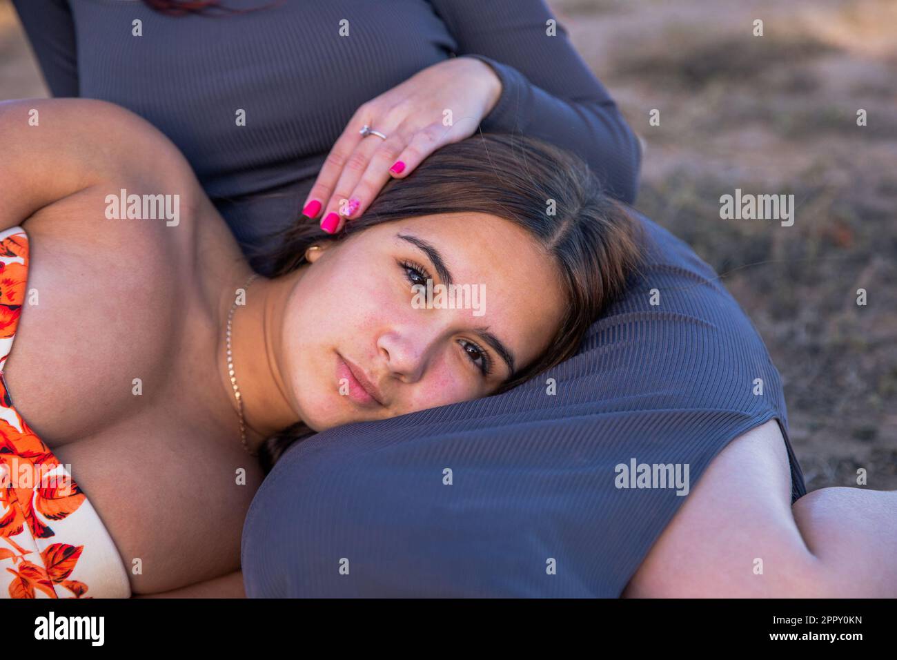 Porträt eines ausdrucksstarken Teenagers, das den Kopf auf den Beinen ihrer Schwester ruht. Stockfoto