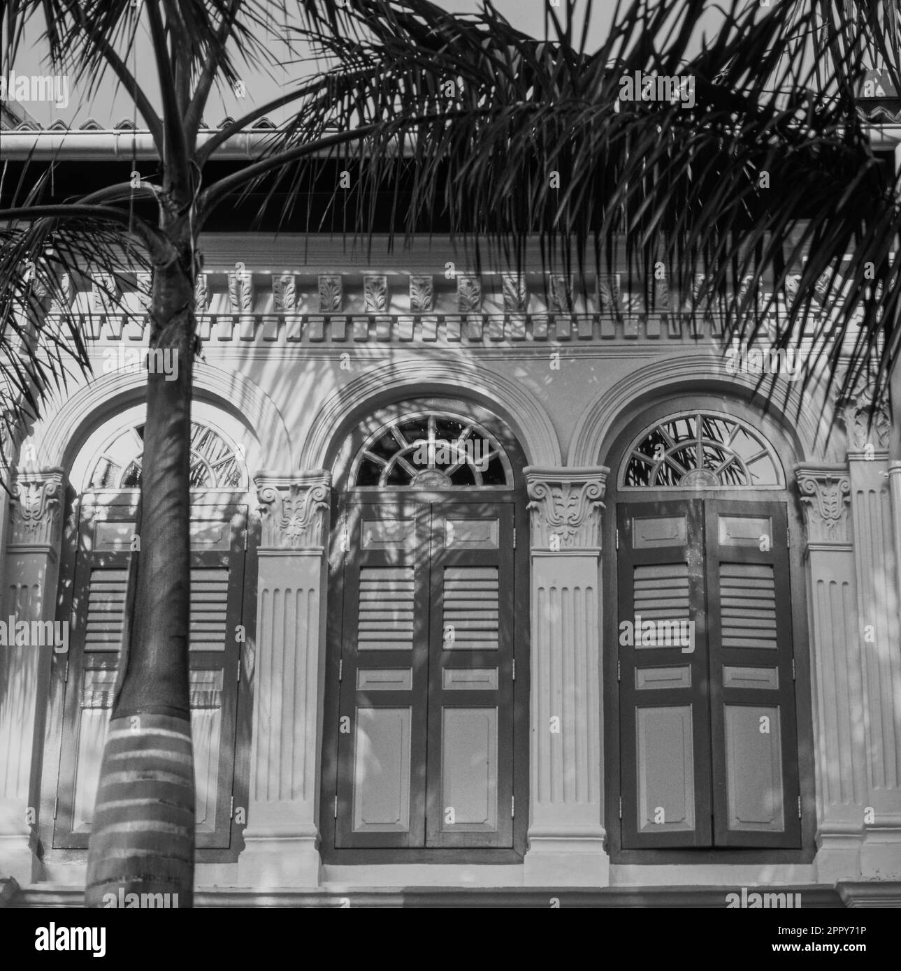 Reihe von Fenstern mit geschlossenen Fensterläden außerhalb des Gebäudes im alten Viertel - Singapur - B&W Stockfoto