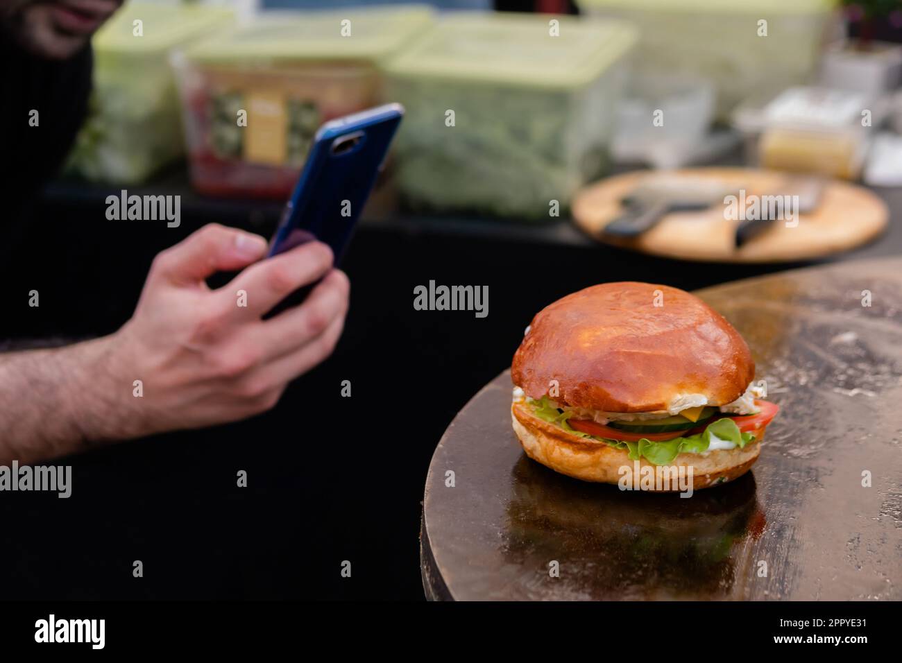 Männerhände fotografieren Burger mit Fisch auf Brazier - Nahaufnahme Stockfoto