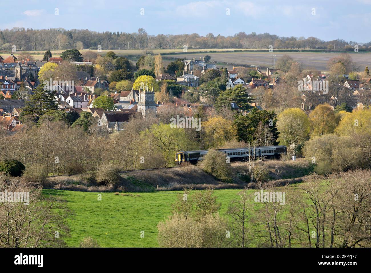 Blick über die Stadt Tisbury im Nadder Valley mit dem Zug im Vordergrund im Frühling, Nachmittagssonnenlicht, Tisbury, Wiltshire, England, Großbritannien Stockfoto