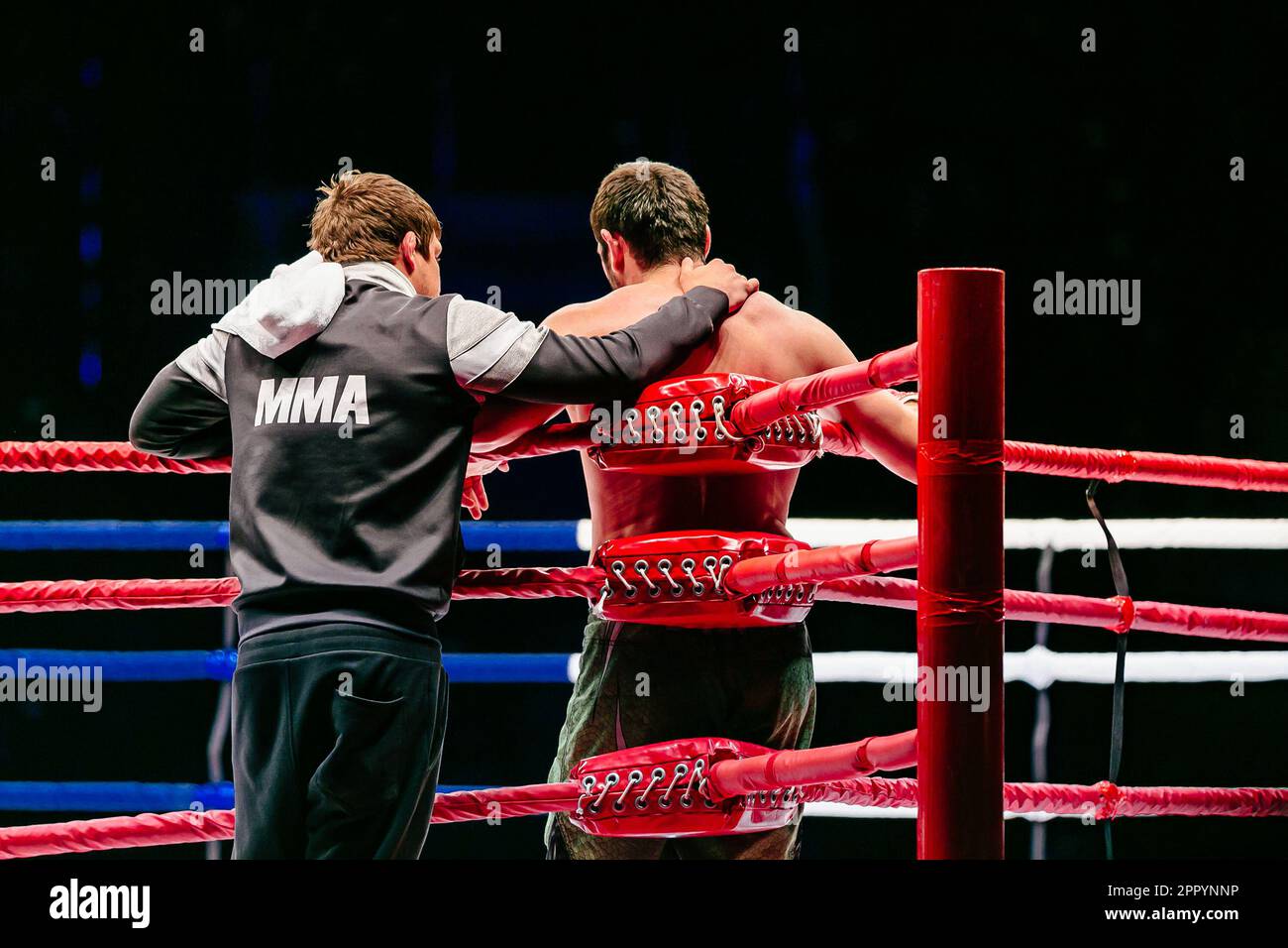 Rückansicht Coach und Kampfstand im roten Eckring in MMA Fighting, Kapuzenpulli mit Aufschrift MMA Stockfoto
