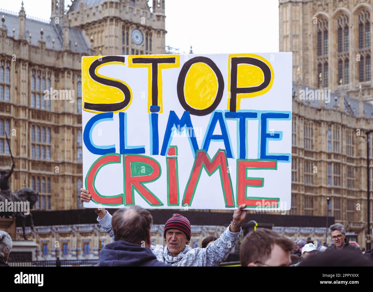 Man hält das Protestplakat "Stop Climate Crime" vor Westminster am Earth Day, Extinction Rebellion Protest Weekend, London, 2023. April. Stockfoto