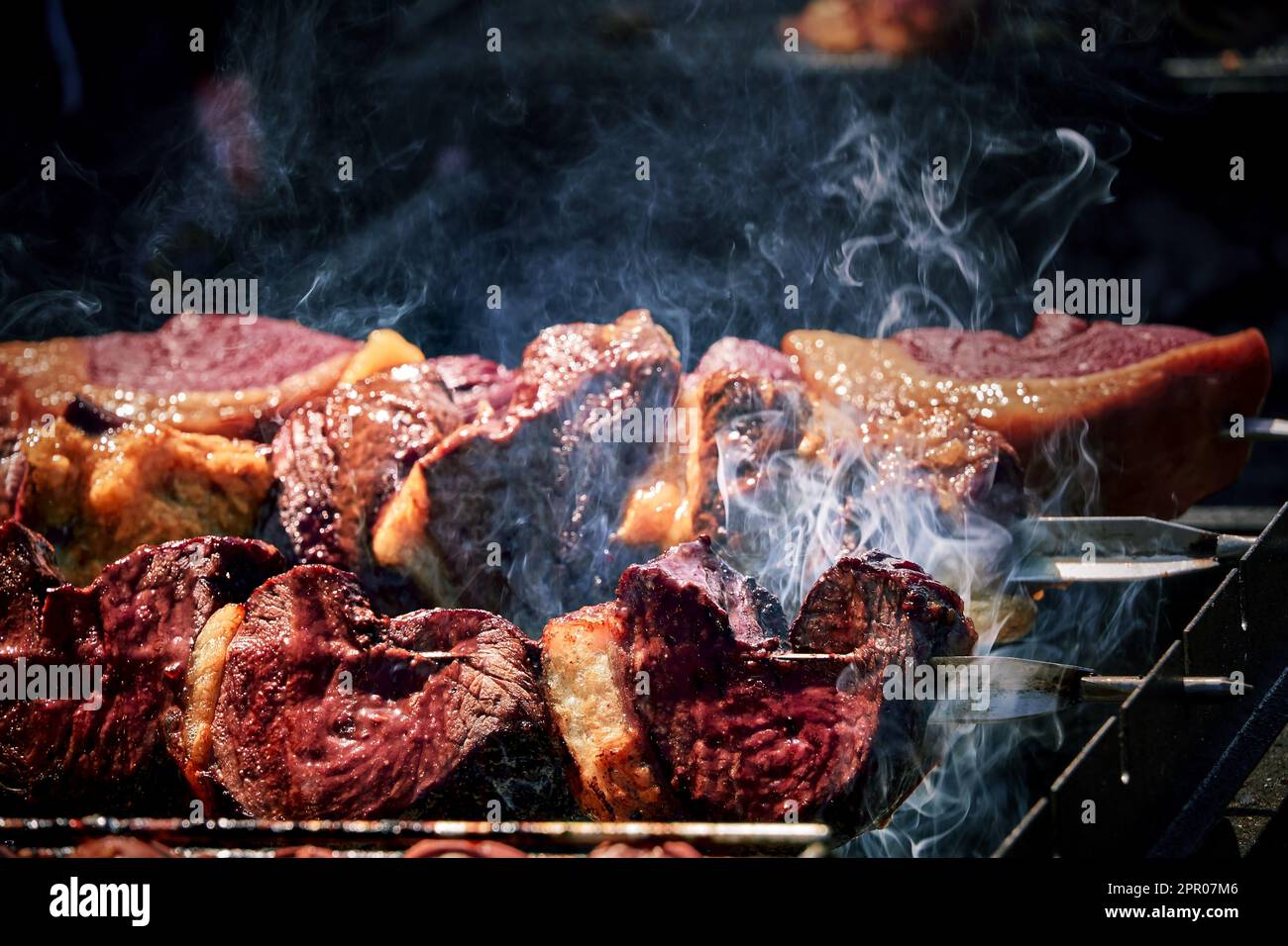 Spiedini di carne sfrigolano sulla brace fumante, emanando un Aroma delizioso. Il calore del fuoco li rende succulenti e teneri Stockfoto