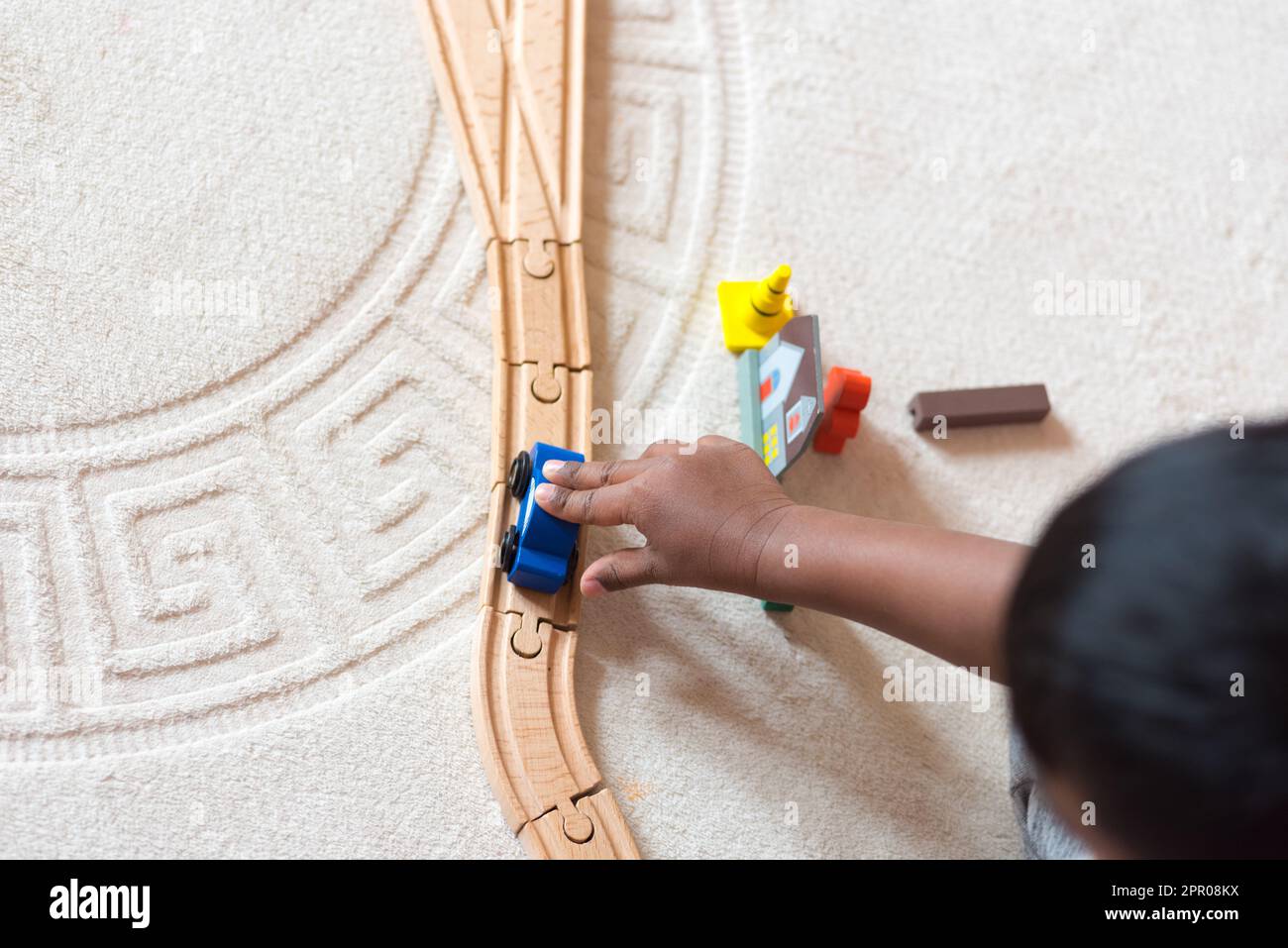 Asiatisches Kind, das mit einer hölzernen Bahnstrecke spielt Stockfoto