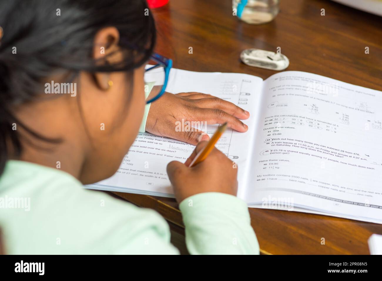 Über die Schultern eines asiatischen Kindes zu schauen, das Hausaufgaben macht Stockfoto