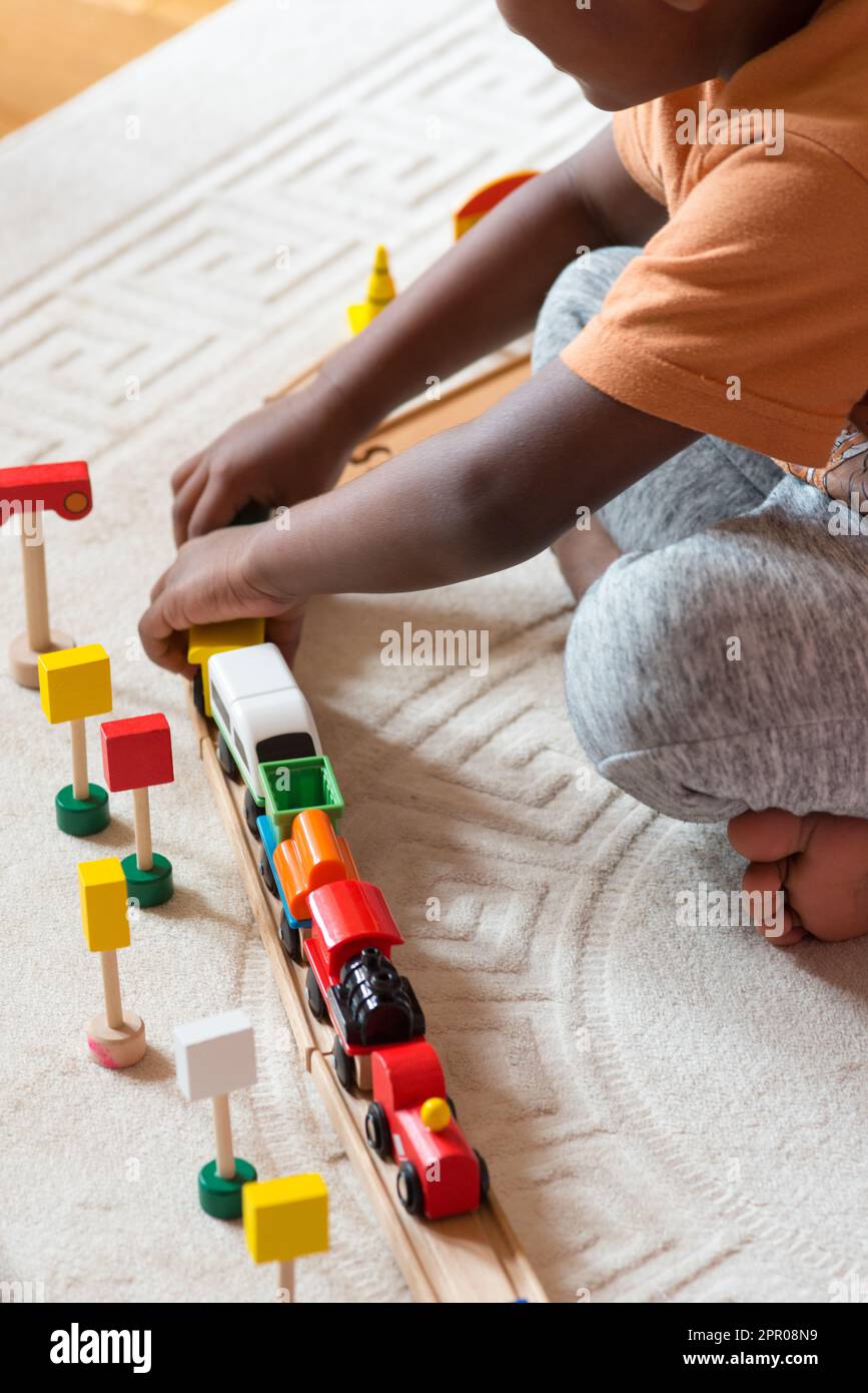 Das Kind stellt die Spielzeuge auf der Zugstrecke auf Stockfoto