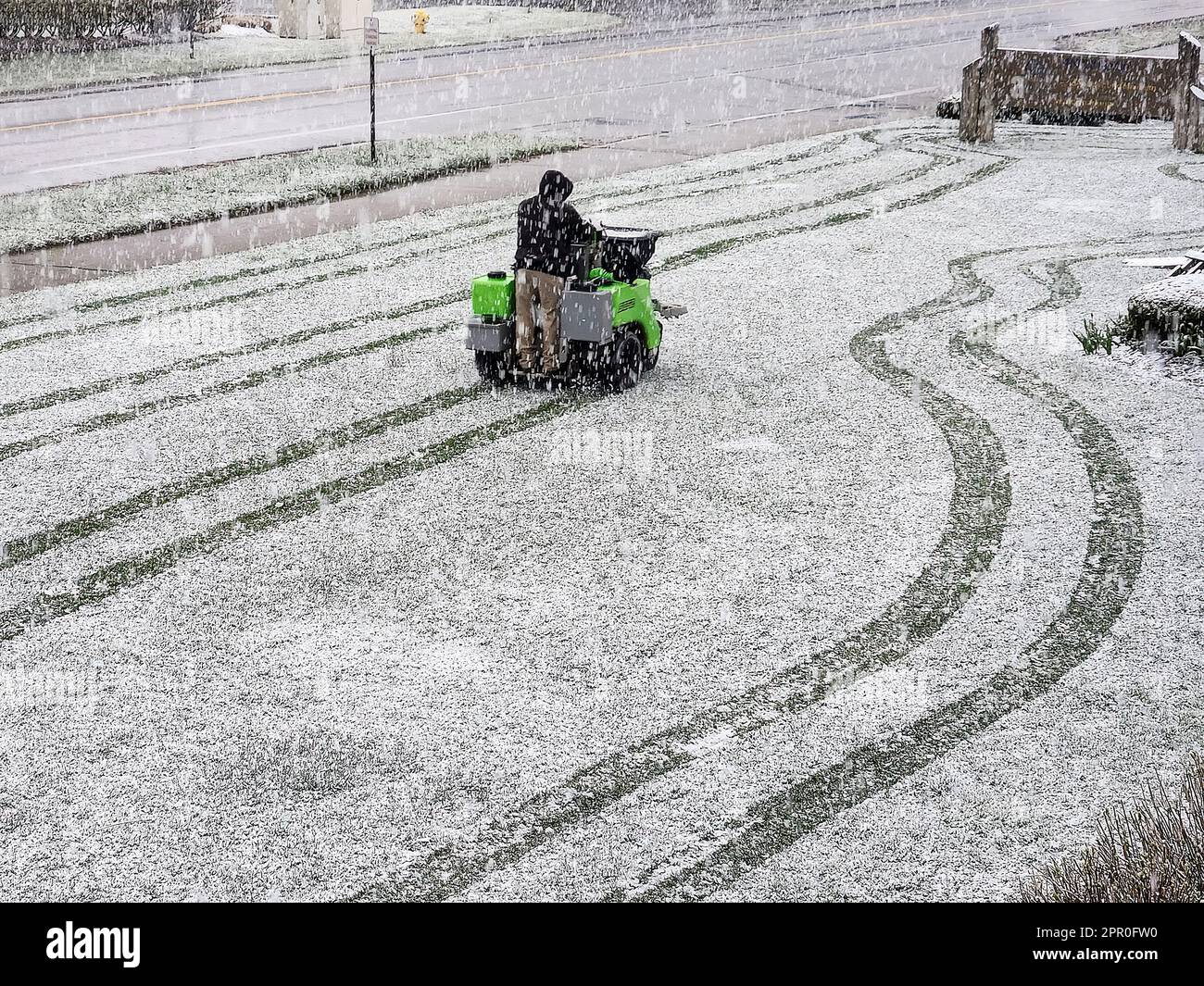 Ein Mann, der in einem Schneesturm auf einem Düngerstreuer reitet Stockfoto