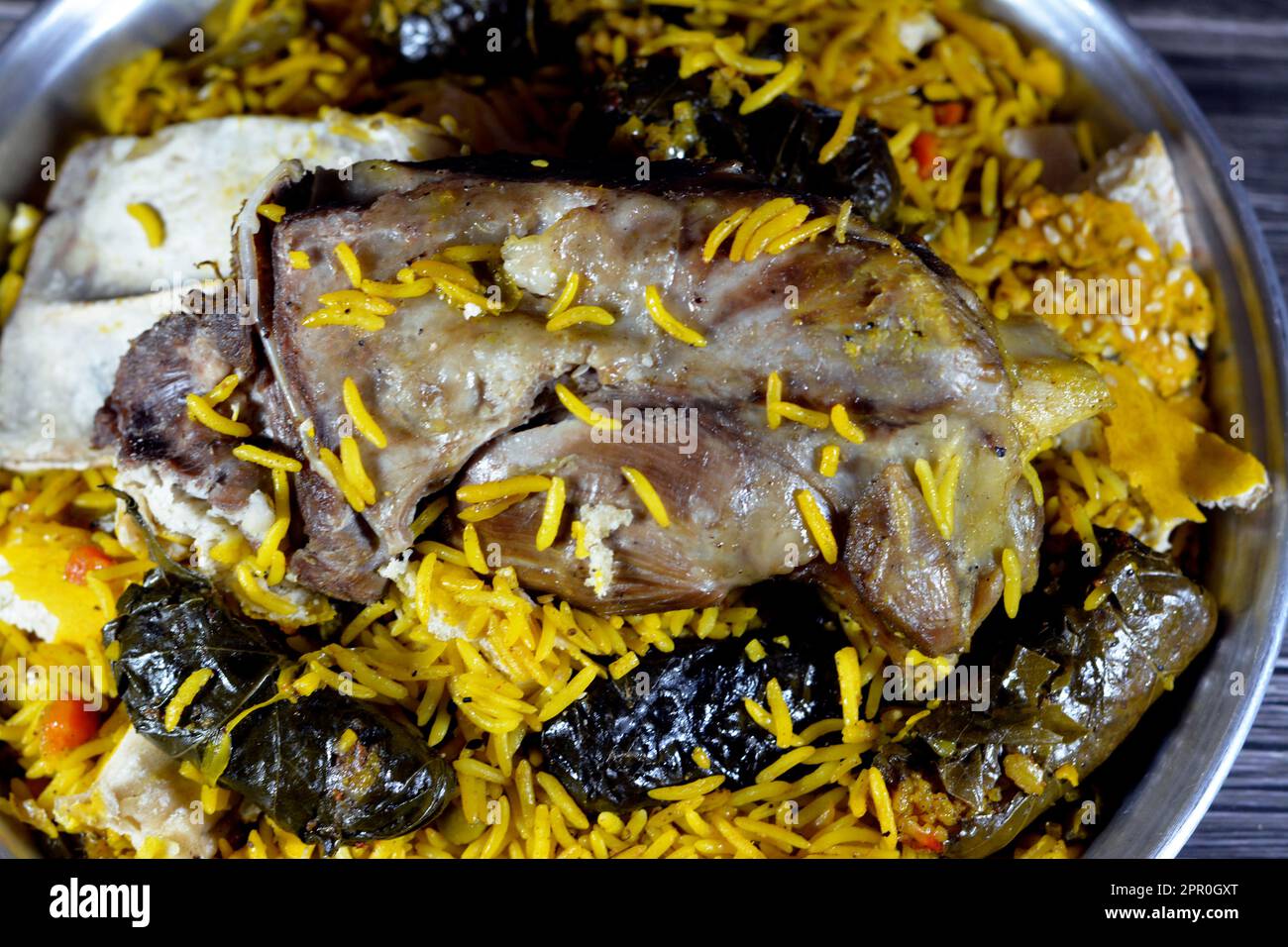 Ein gut gekochter Lammschaft mit gelbem Basmati-Reis und gemischtem Gemüse und gefüllten Traubenblättern Mahshi Mahshy mit weißem Reis, der im OV geröstet wird Stockfoto