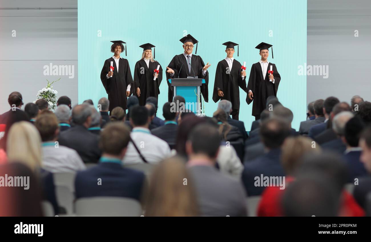 Professor und Studenten stehen auf einem Podium vor den Leuten im Publikum Stockfoto